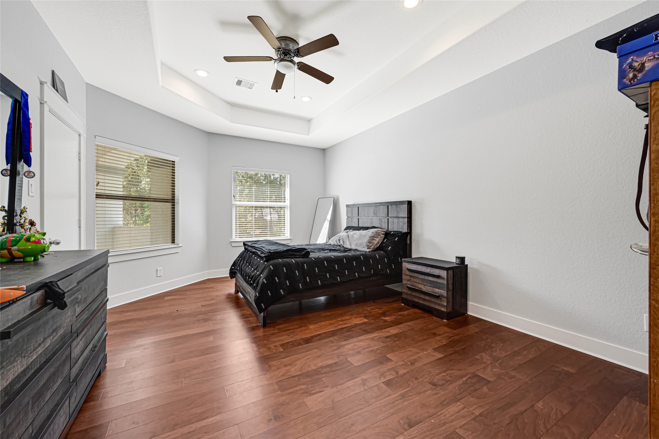 Comfortable bedroom with wood flooring, a ceiling fan, and space for additional furnishings.