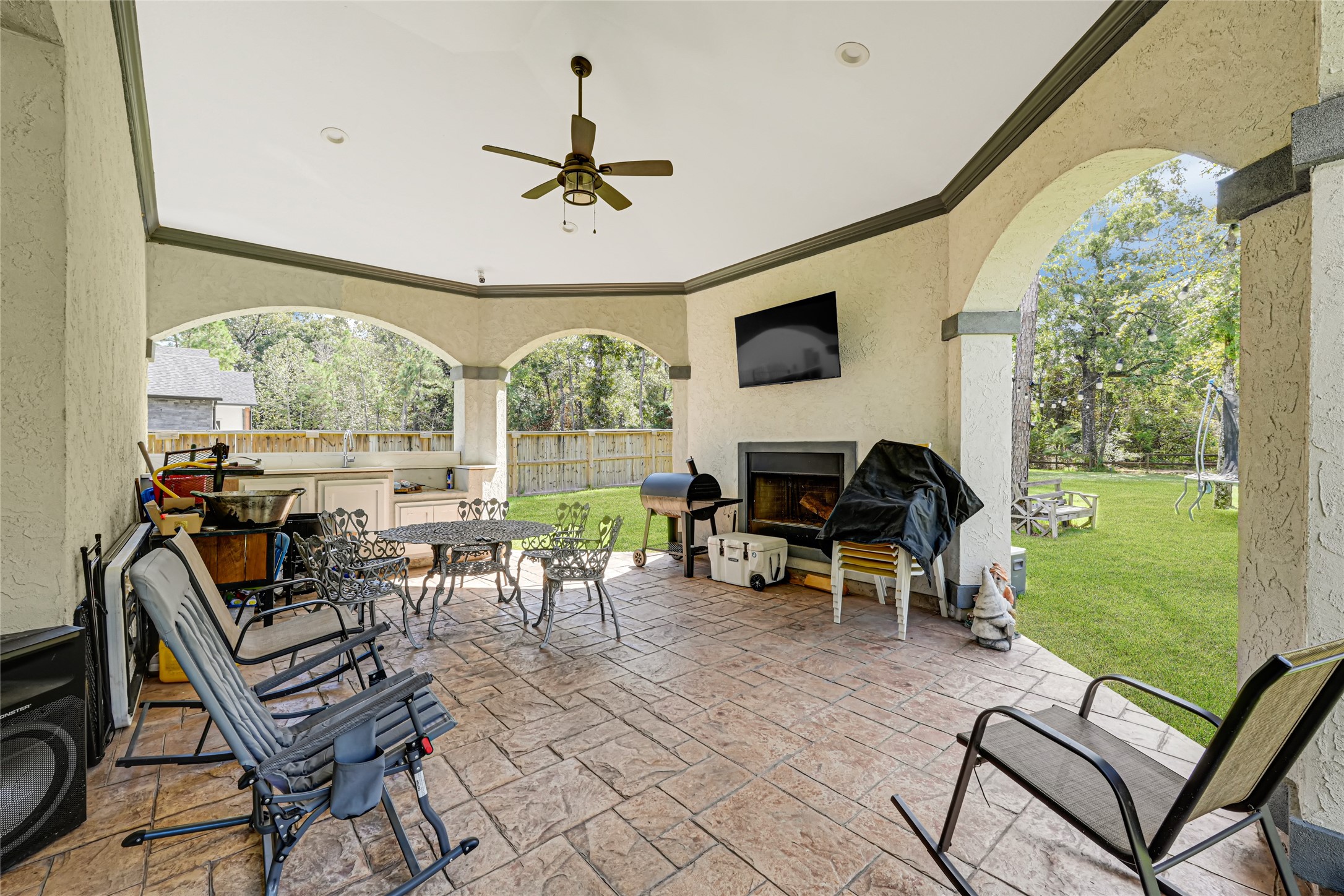 Covered rear patio with a ceiling fan offers space for outdoor seating and views of the backyard.