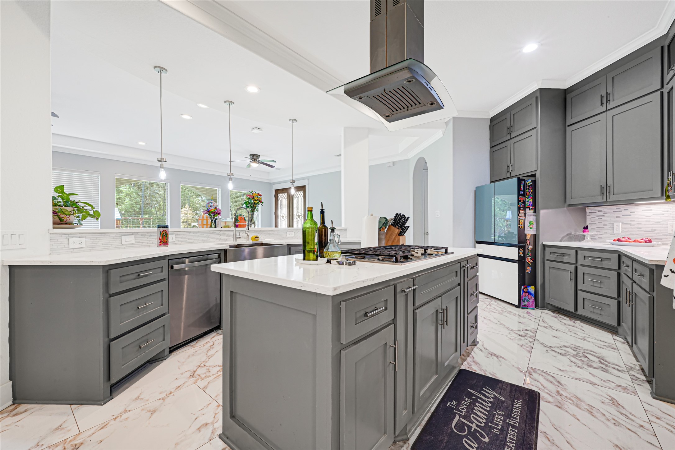 Island cooktop with a statement vent hood anchors the kitchen, complemented by ample storage and workspace.