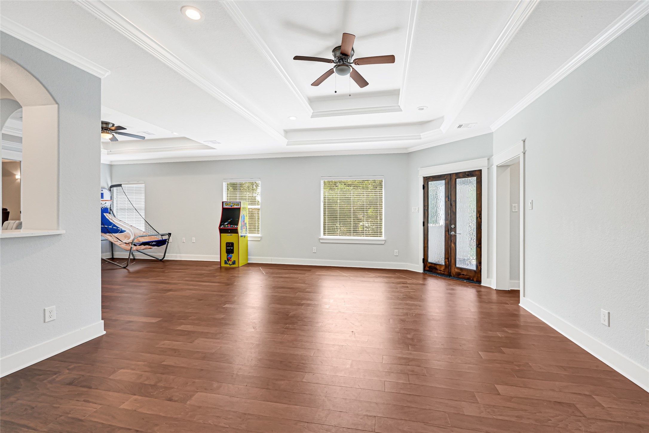 Spacious upstairs game room with wood flooring and balcony access offers plenty of room for recreation and entertaining.