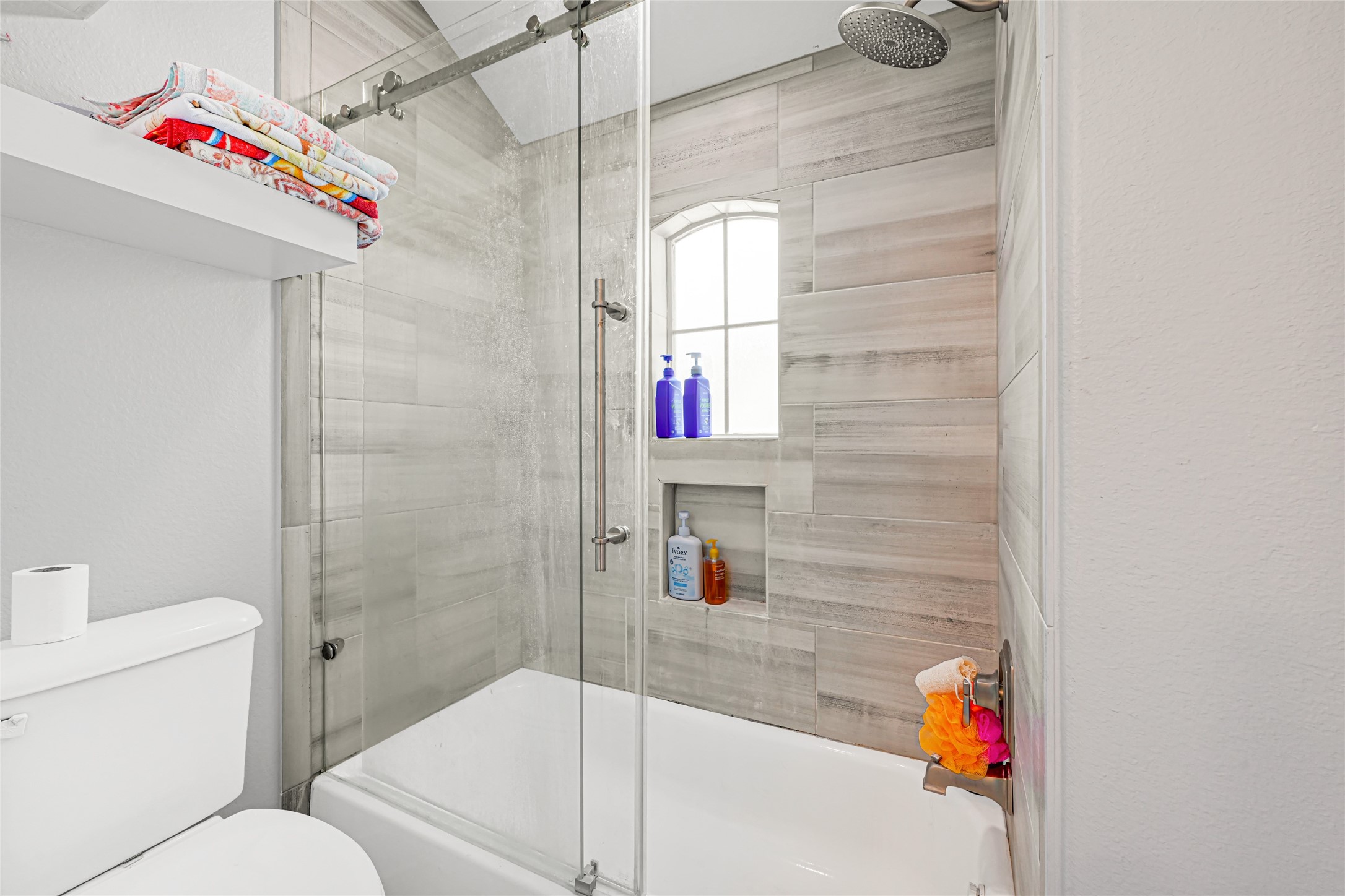 Tub and shower combination with a tiled surround and built-in niches for convenient storage.