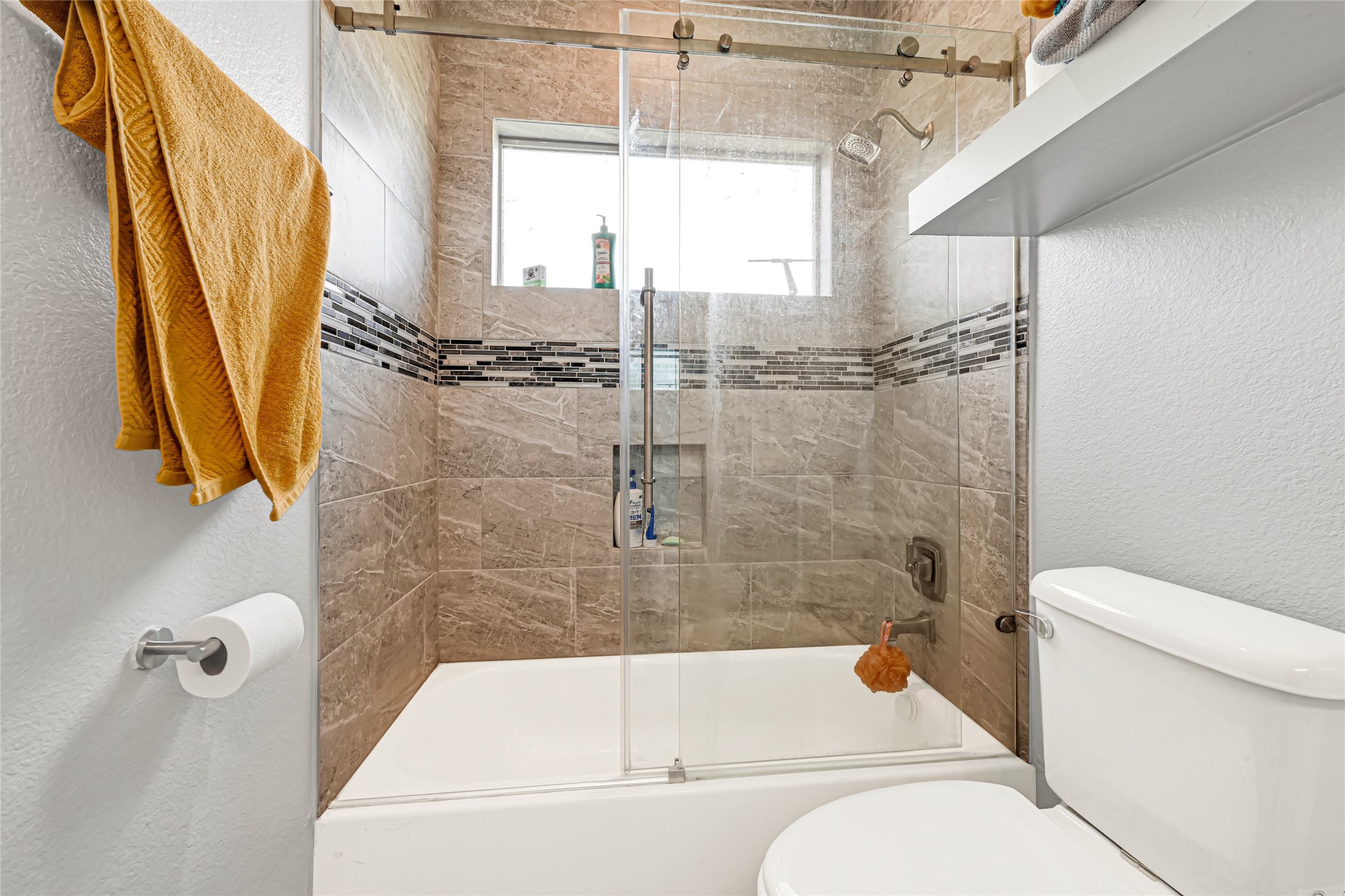 Tub and shower combination with tile surround and a window for natural light.