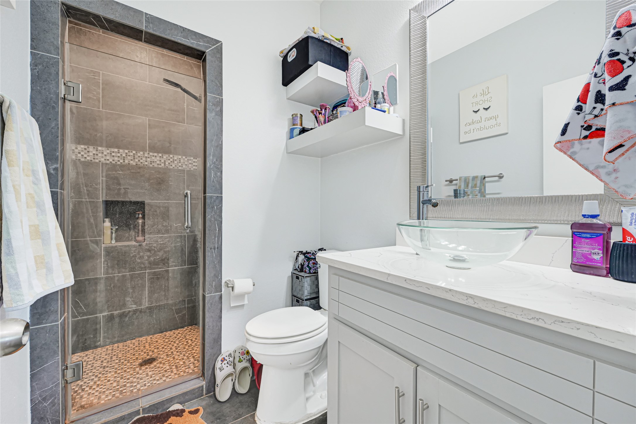 Bathroom features a vanity with cabinet storage and a separate tiled shower.