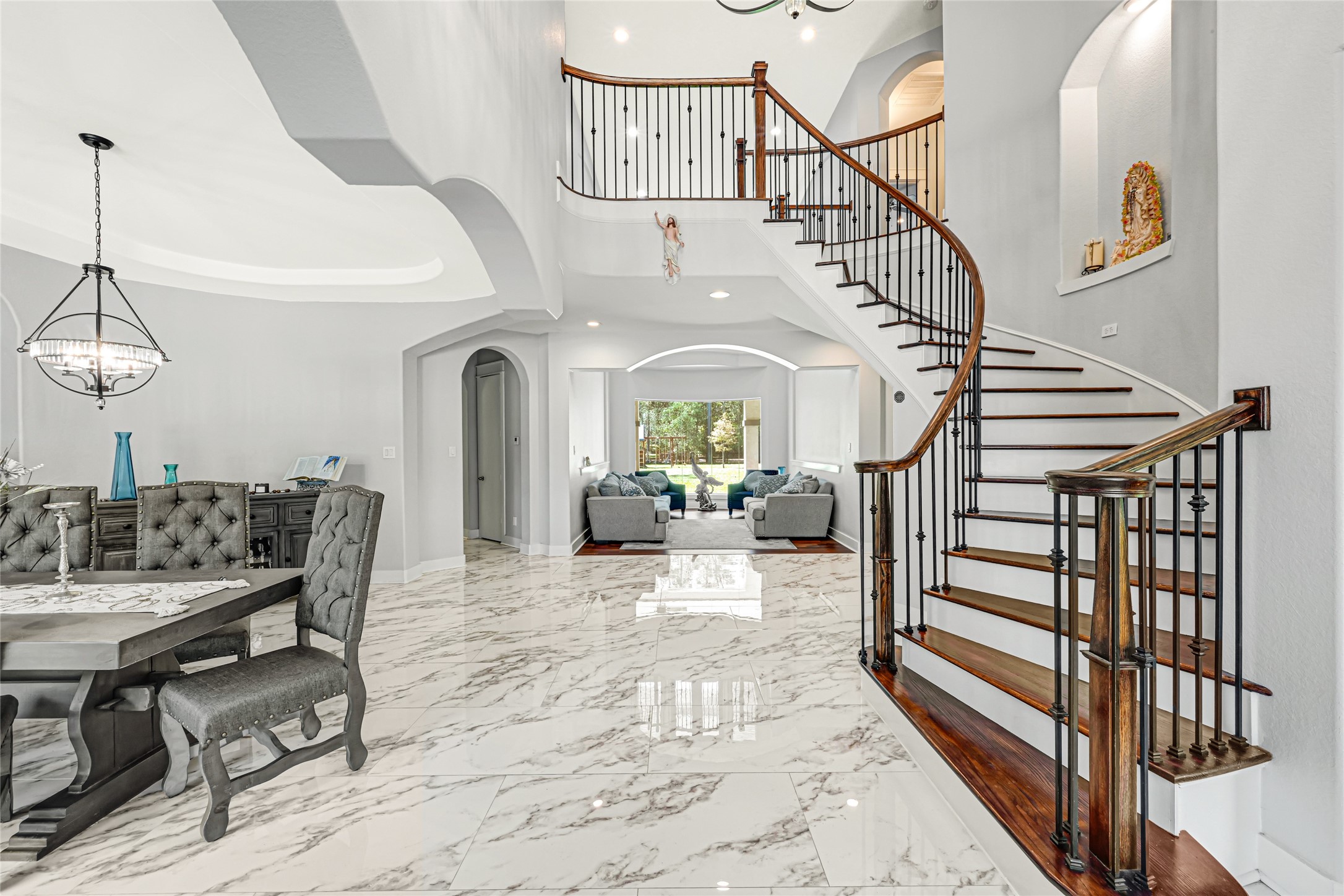 An impressive foyer welcomes guests with a sweeping staircase and decorative iron railing.