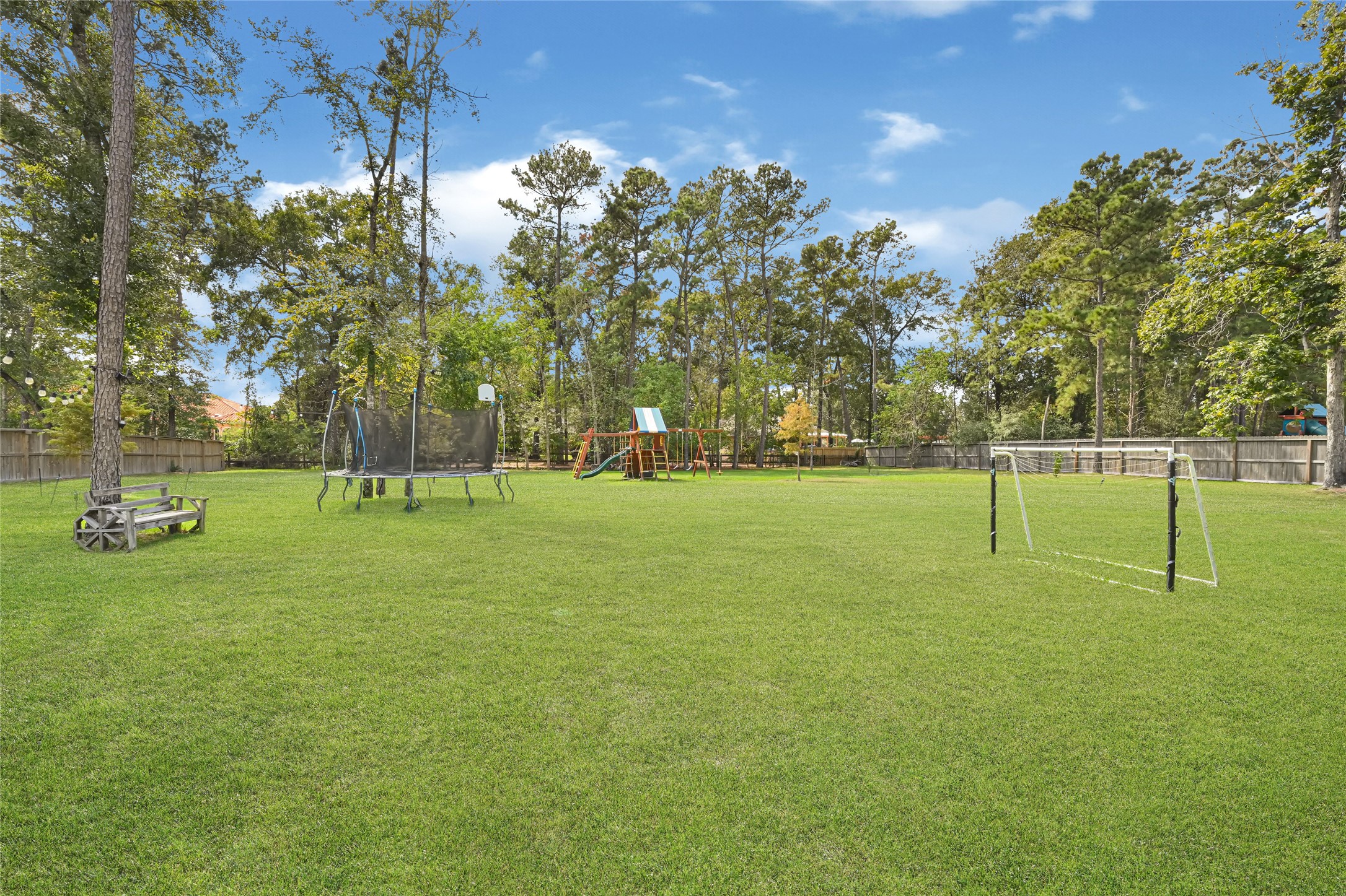 Expansive backyard offers open green space bordered by mature trees.