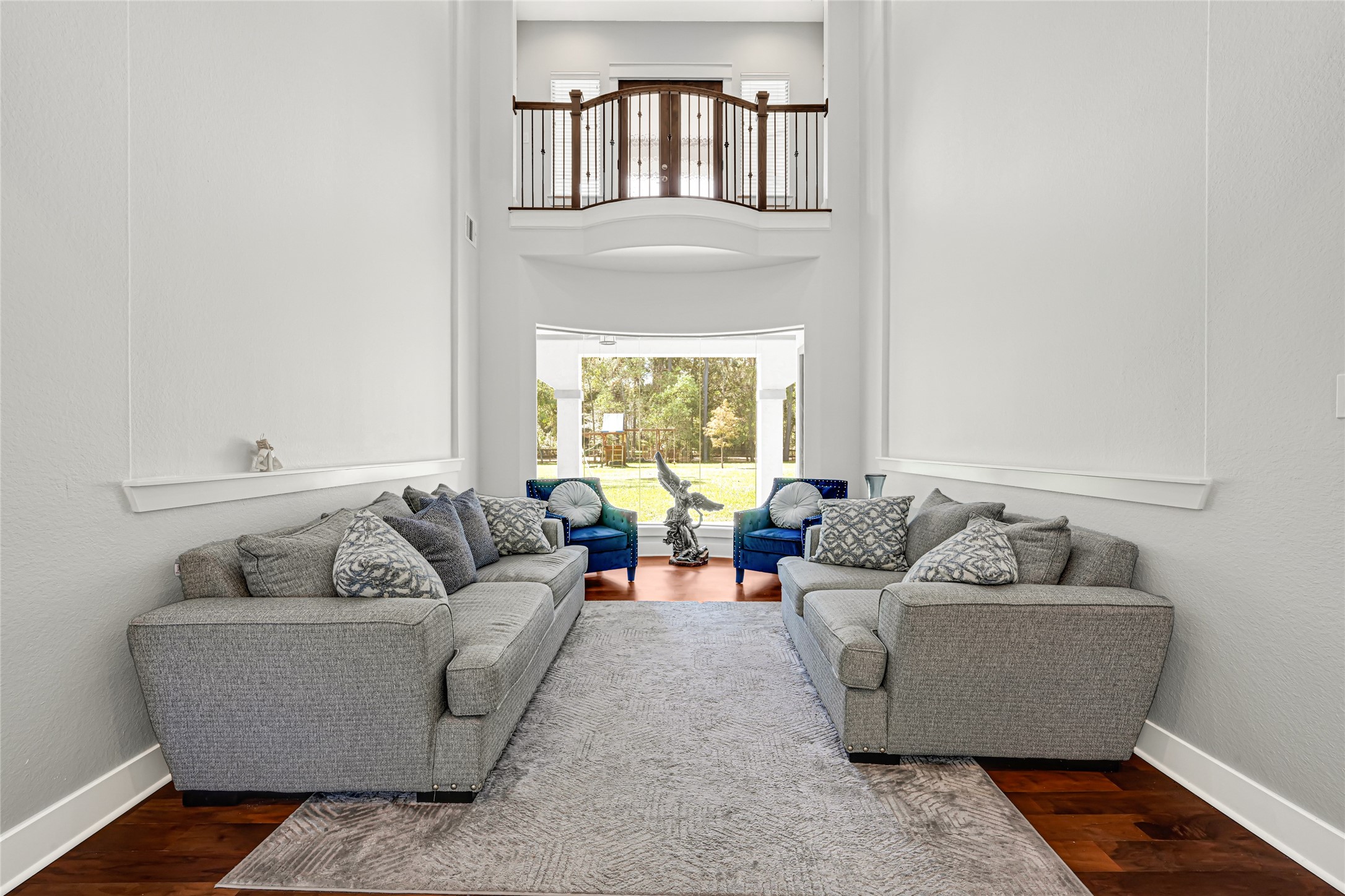 Formal living room features soaring ceilings and a tall window that fills the space with natural light.