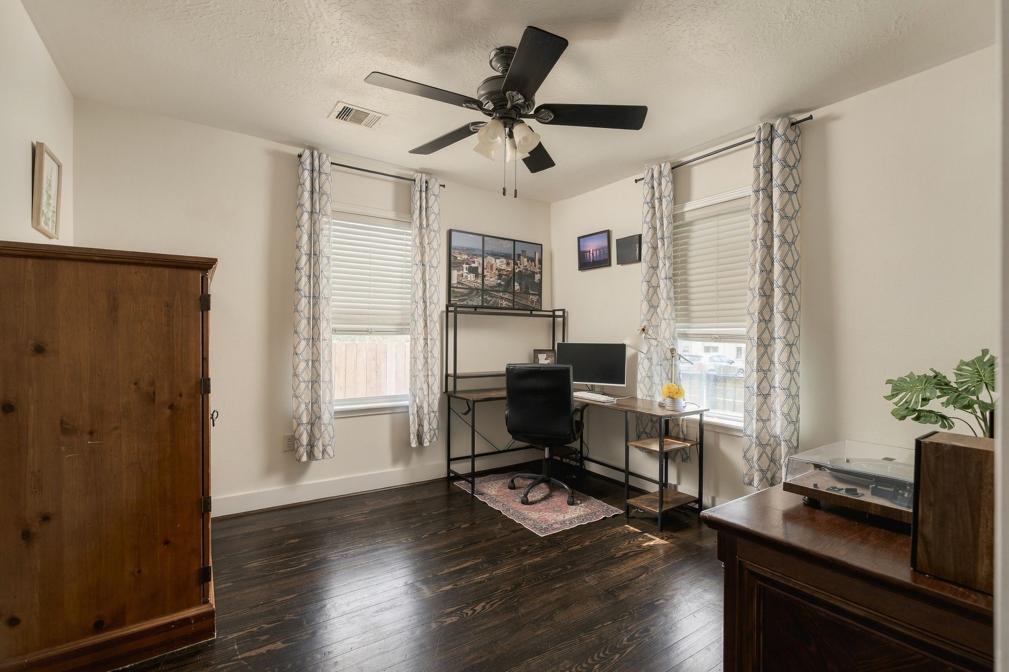 Light-filled secondary bedroom with windows along two walls, currently arranged as a home office. An ideal flex space for working from home, accommodating guests, or creating a personal retreat.