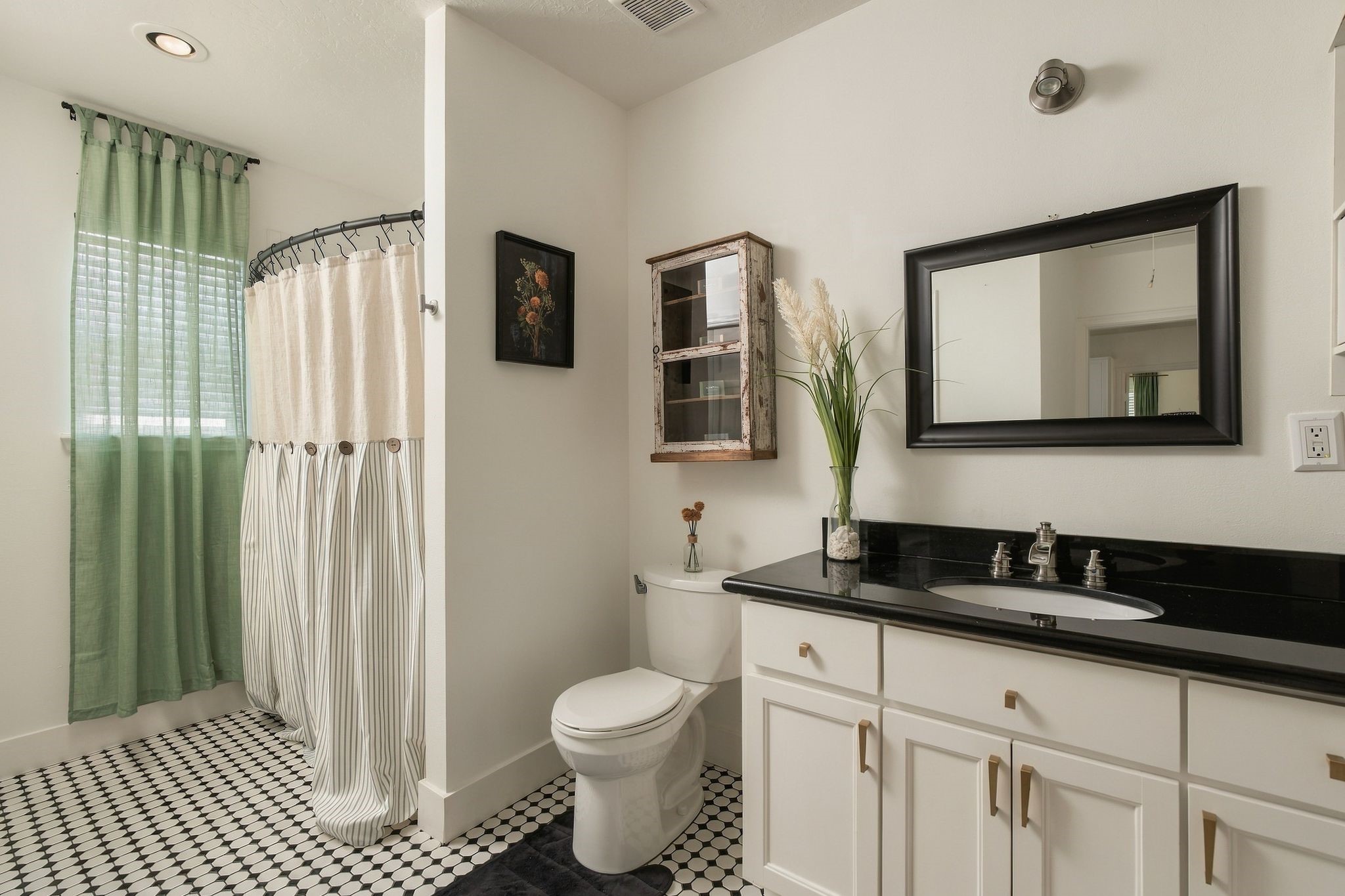 Full secondary bathroom with tub-shower combination, vanity storage, and a dedicated utility closet accommodating a full-size washer and dryer, plus additional storage. A practical feature in this historic bungalow.