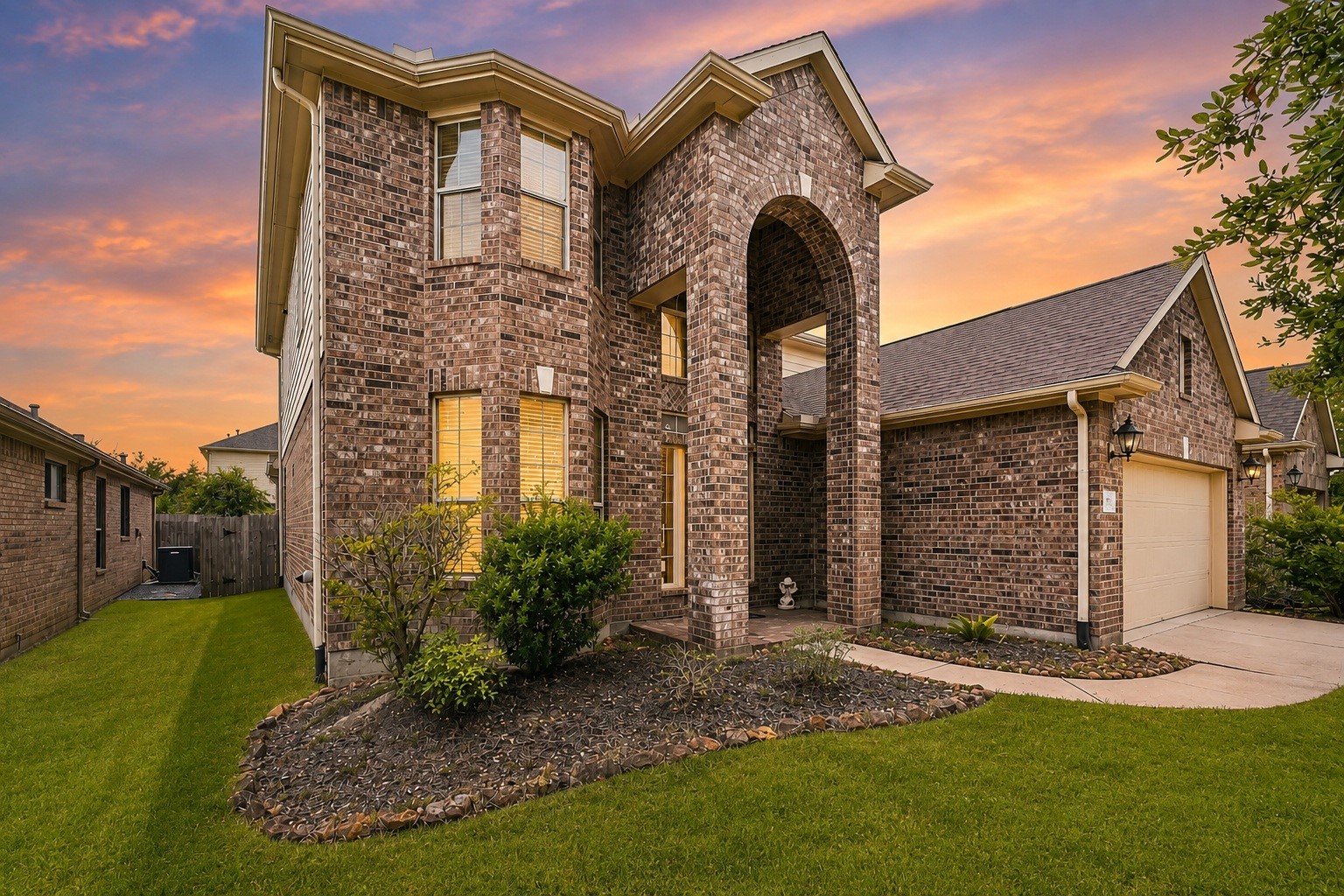Feel instantly at home in this handsome brick residence. A magnificent arched entryway provides a warm, covered welcome, while the multi-level windows frame a glimpse of the cheerful, light-filled spaces within.