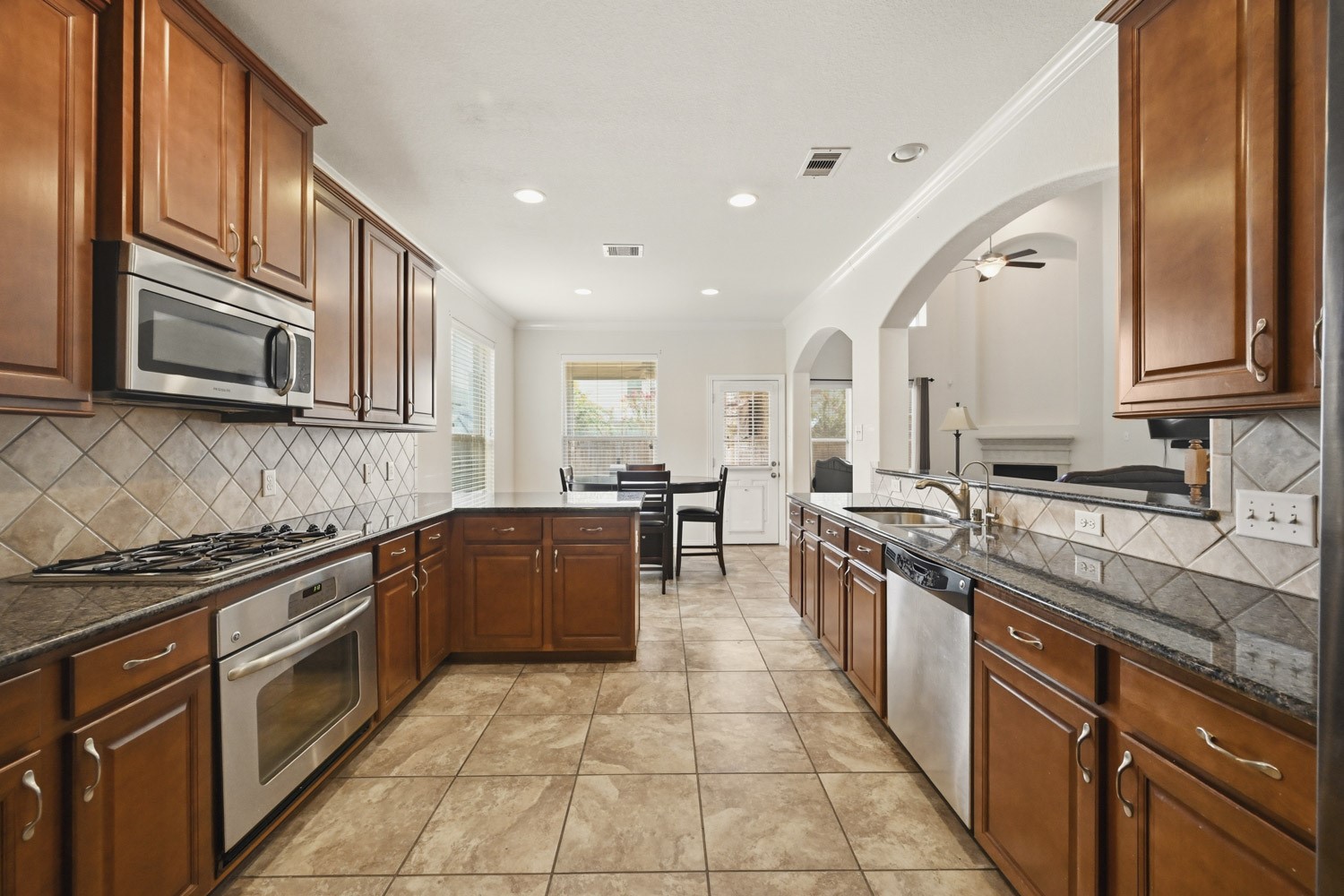 The spacious galley-style layout flows effortlessly into a sunny breakfast nook with outdoor access, while wide architectural arches open up direct sightlines into the living room.