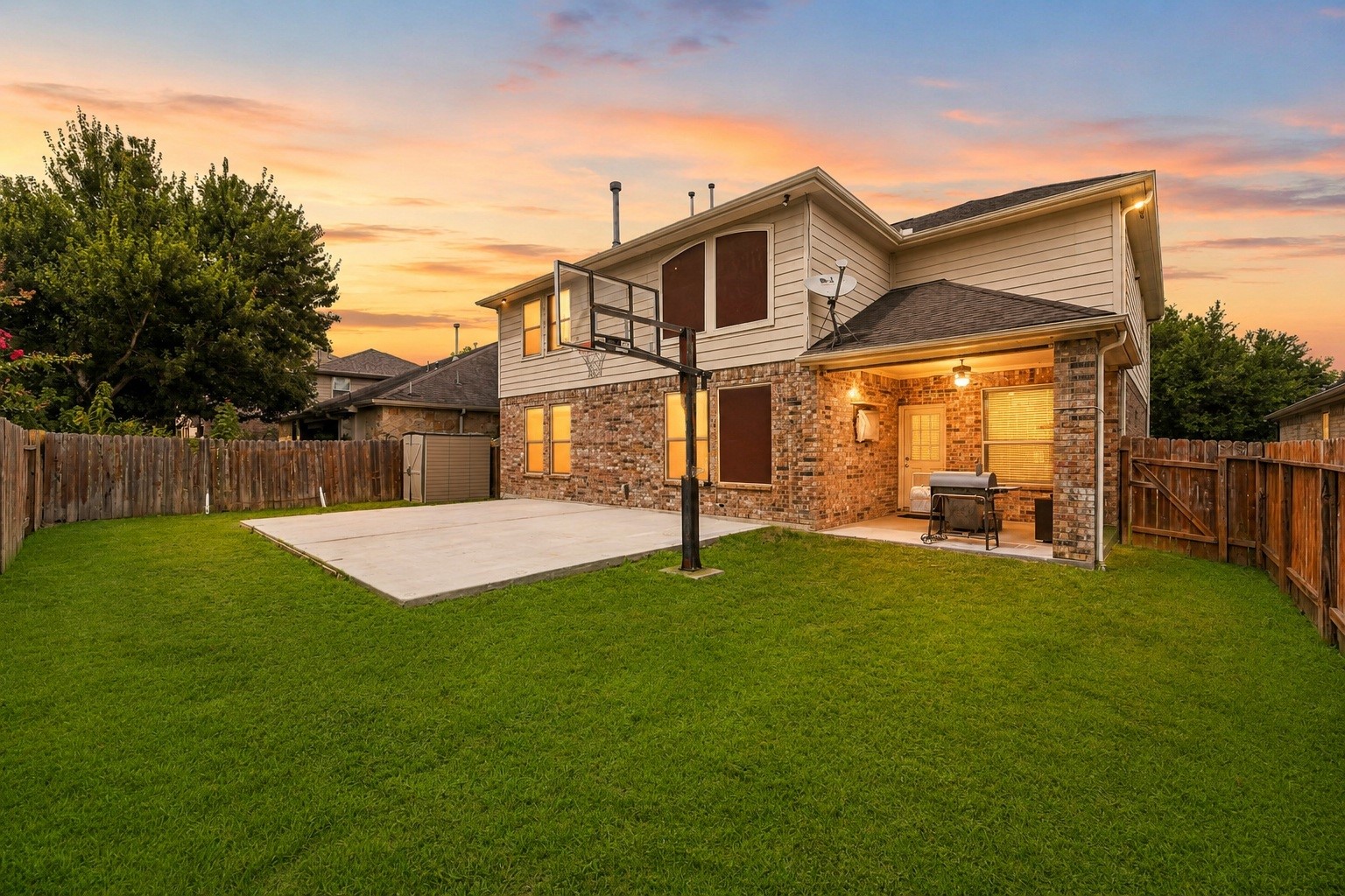 Enjoy remarkable space and privacy in this sprawling backyard setup. Featuring a combination of a sheltered patio, an extended concrete court area, a dedicated storage shed, and a broad lawn surrounded by privacy fencing.