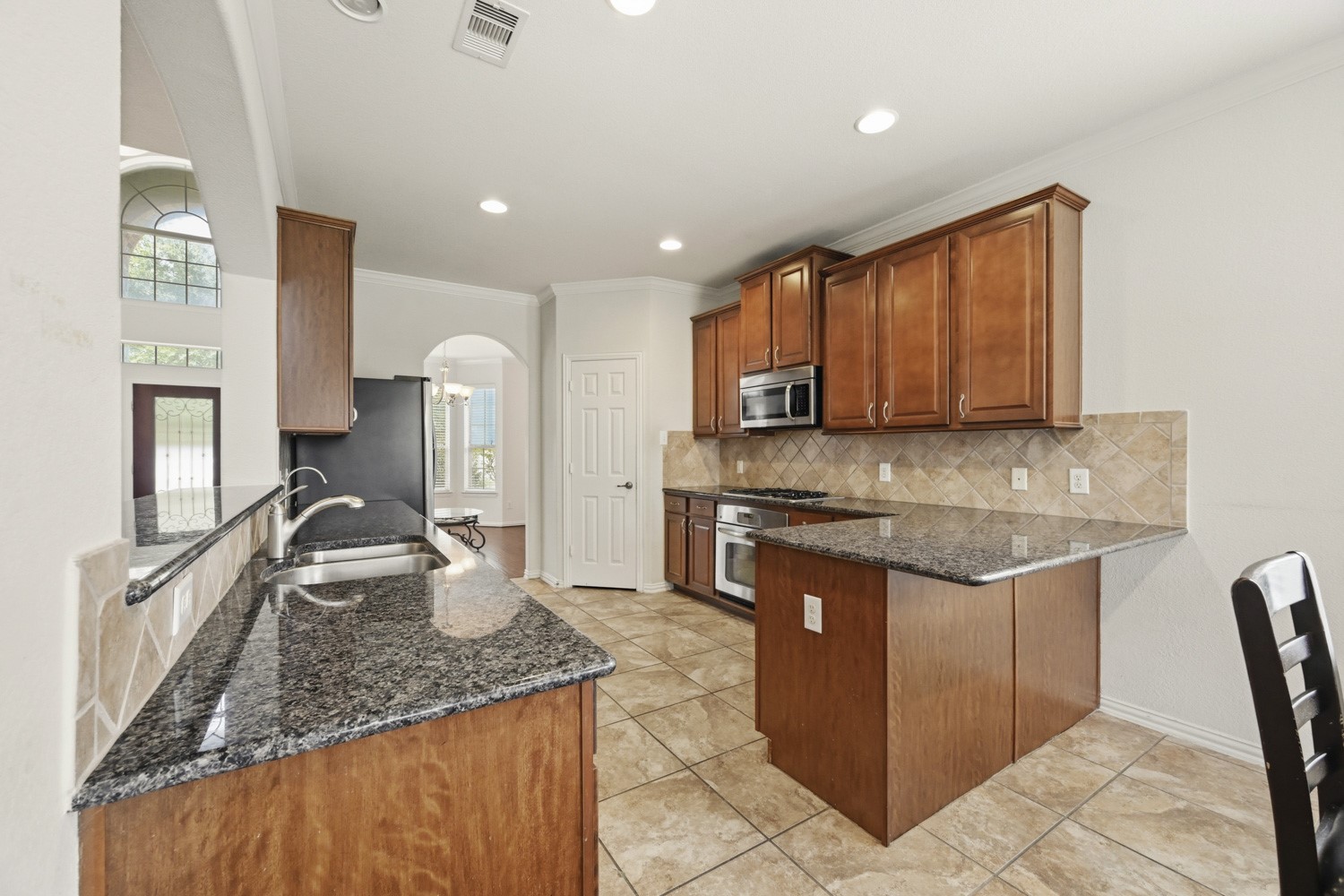 This warm and spacious kitchen serves as an inviting centerpiece for everyday living. The open wrap-around layout combines ample counter space with a dedicated breakfast bar peninsula for casual dining.