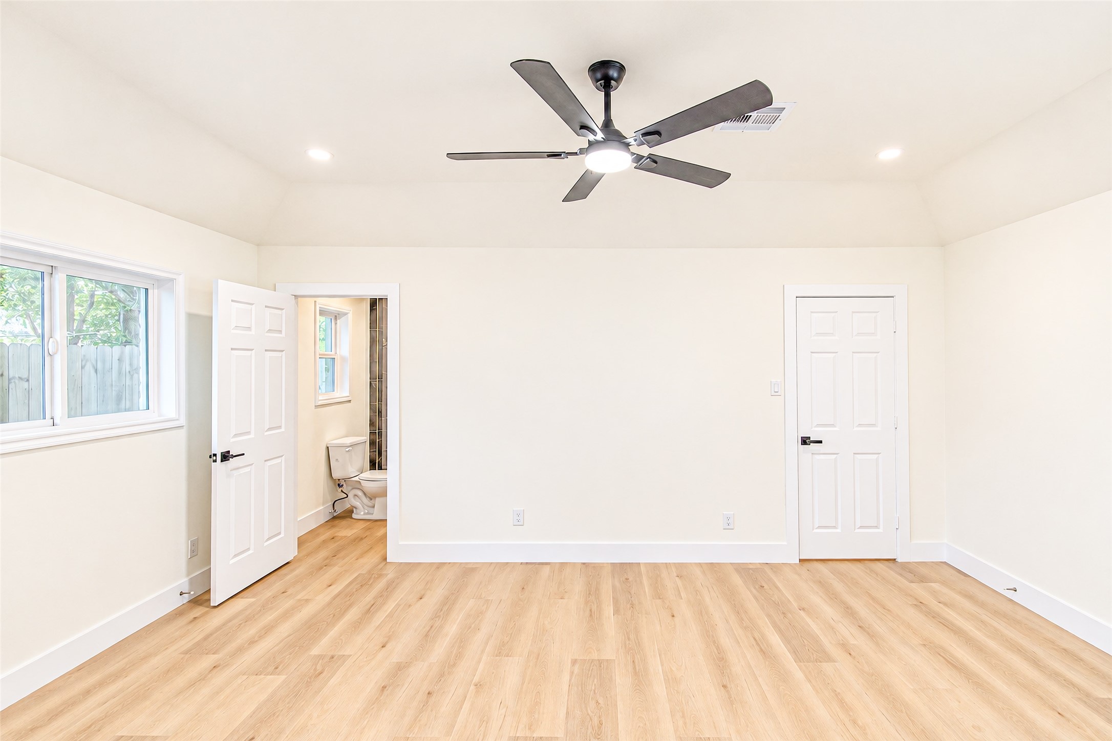 Spacious primary bedroom with sleek hardwood floors, abundant natural light, and an ensuite bathroom for ultimate comfort.