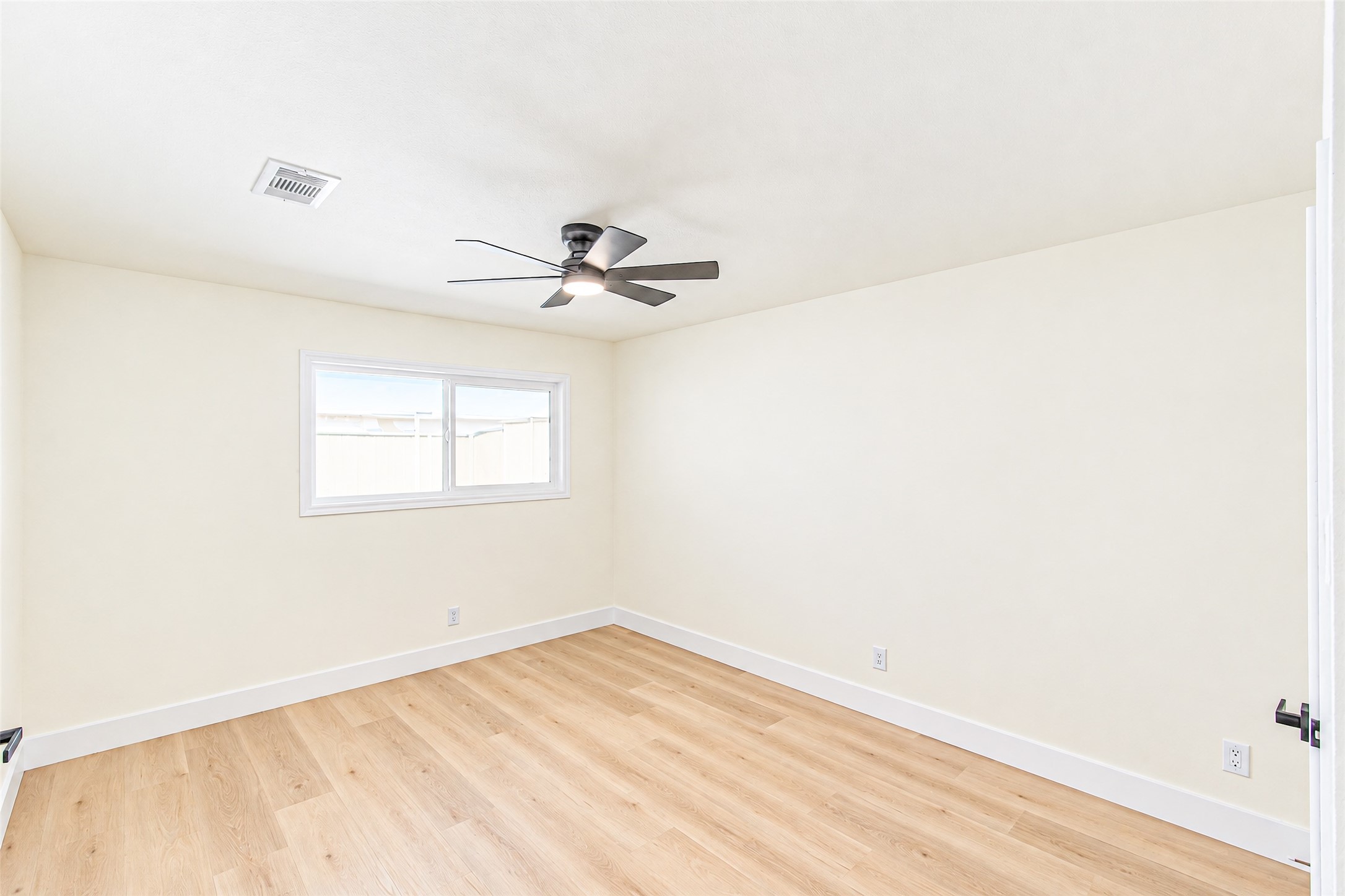 Bedroom 4 offers a bright and airy space with sleek wood flooring and a modern ceiling fan, perfect for relaxation.