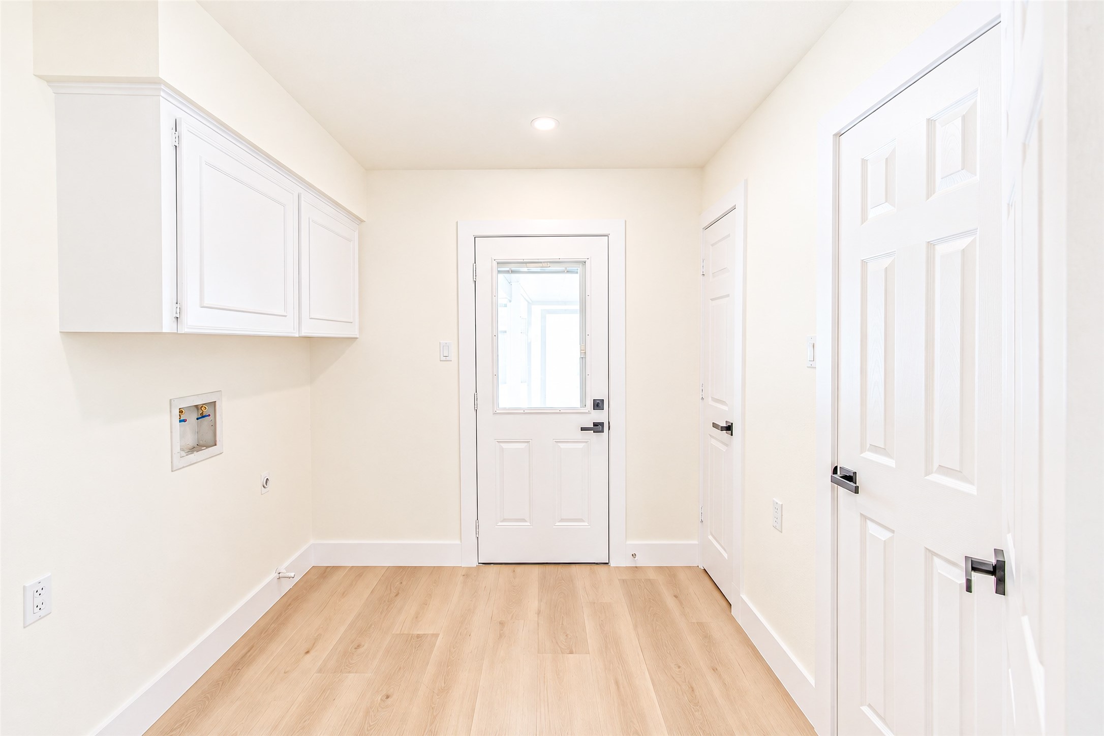 Bright and spacious, this pristine laundry room features modern cabinetry and sleek flooring, offering both functionality and style.
