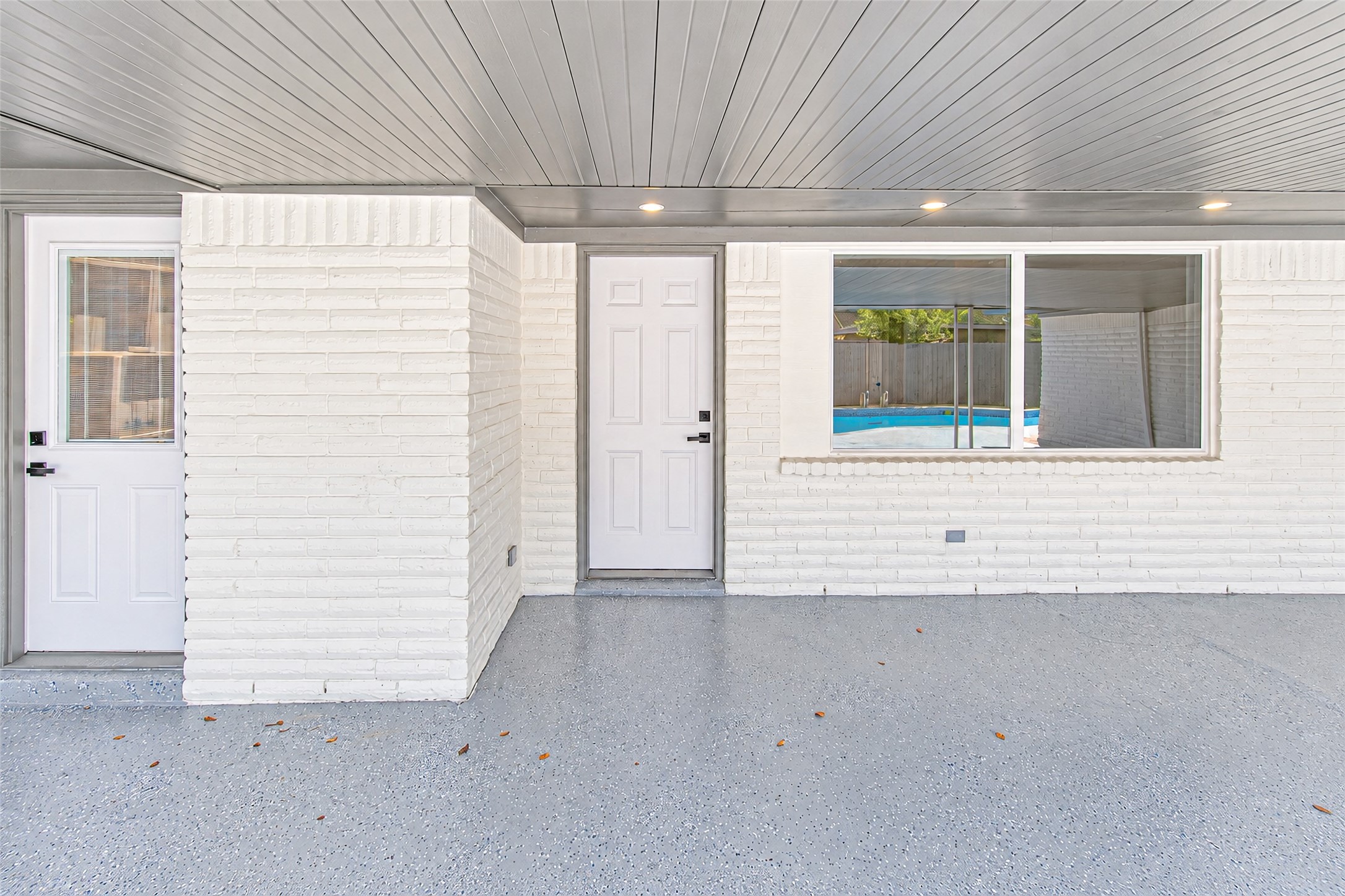 Charming covered patio area with modern white brickwork and a view of the inviting pool, perfect for outdoor relaxation and entertainment.