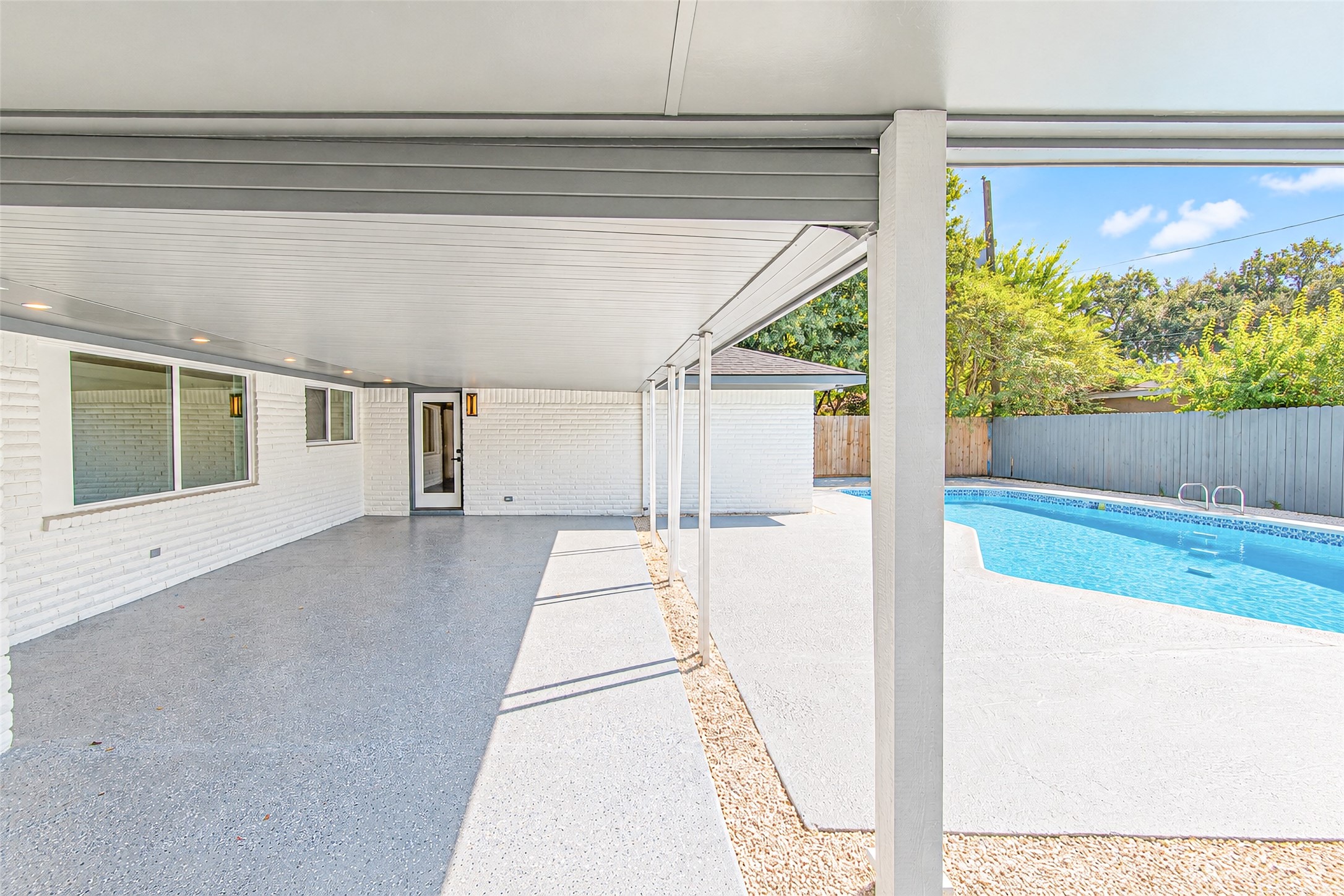 Enjoy serene outdoor living with a spacious covered patio overlooking a sparkling pool, perfect for relaxation and entertaining.