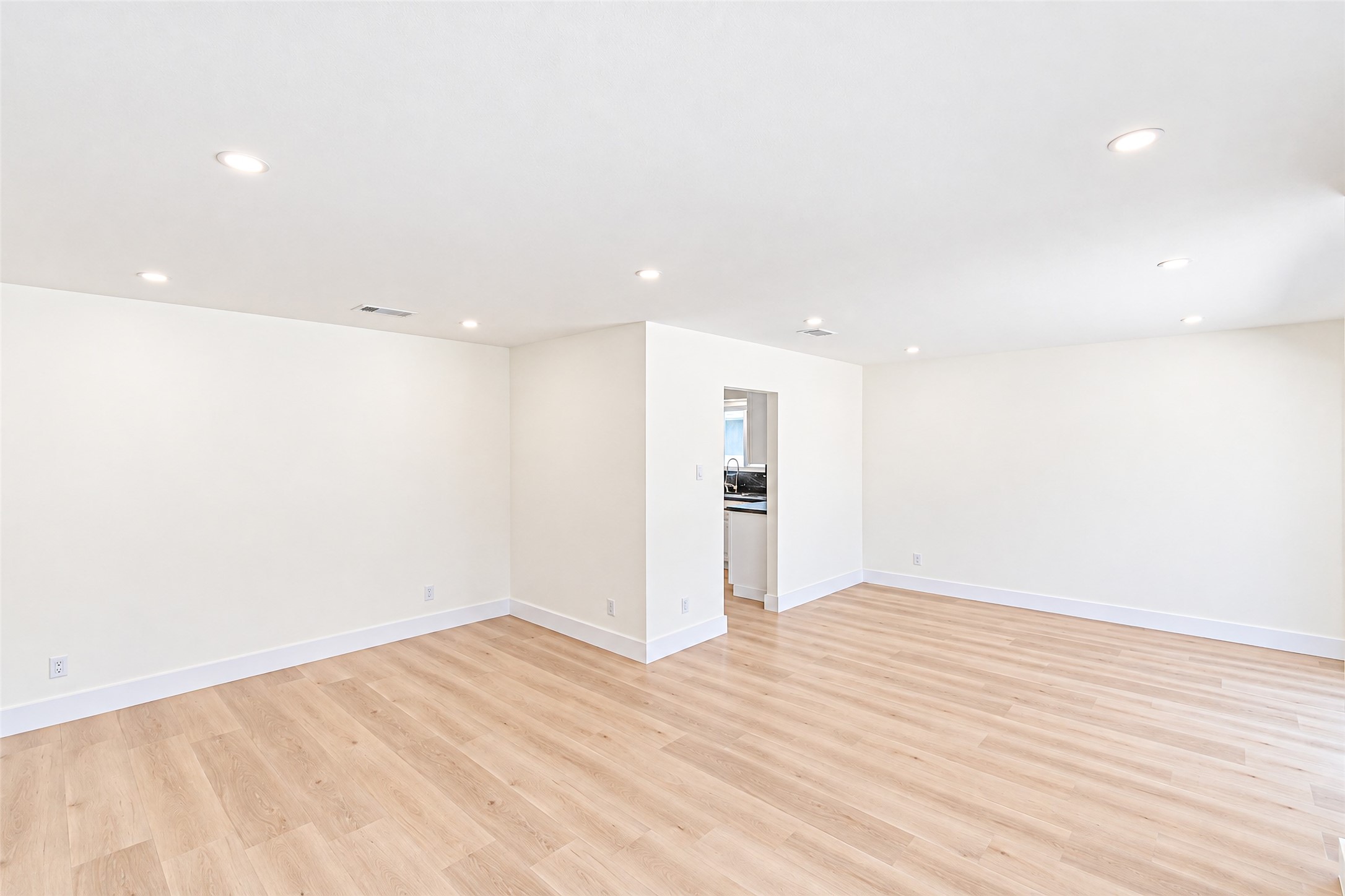 A spacious dining room bathed in natural light, featuring elegant wood flooring and seamless flow into the kitchenperfect for entertaining and creating cherished memories.