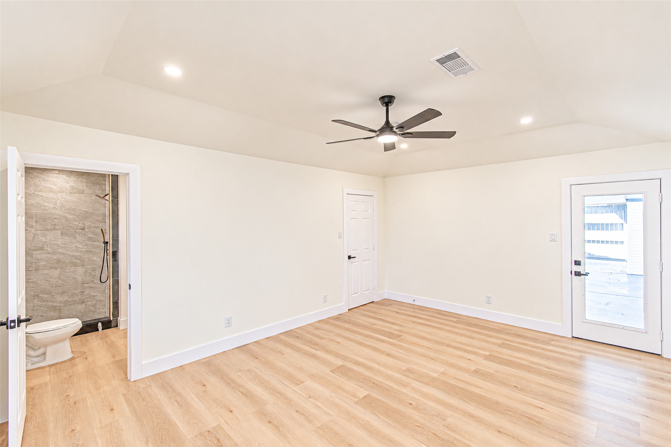 Experience the serenity of this spacious primary bedroom, featuring elegant hardwood floors, a sleek ceiling fan, and direct access to a luxurious en-suite bathroom.