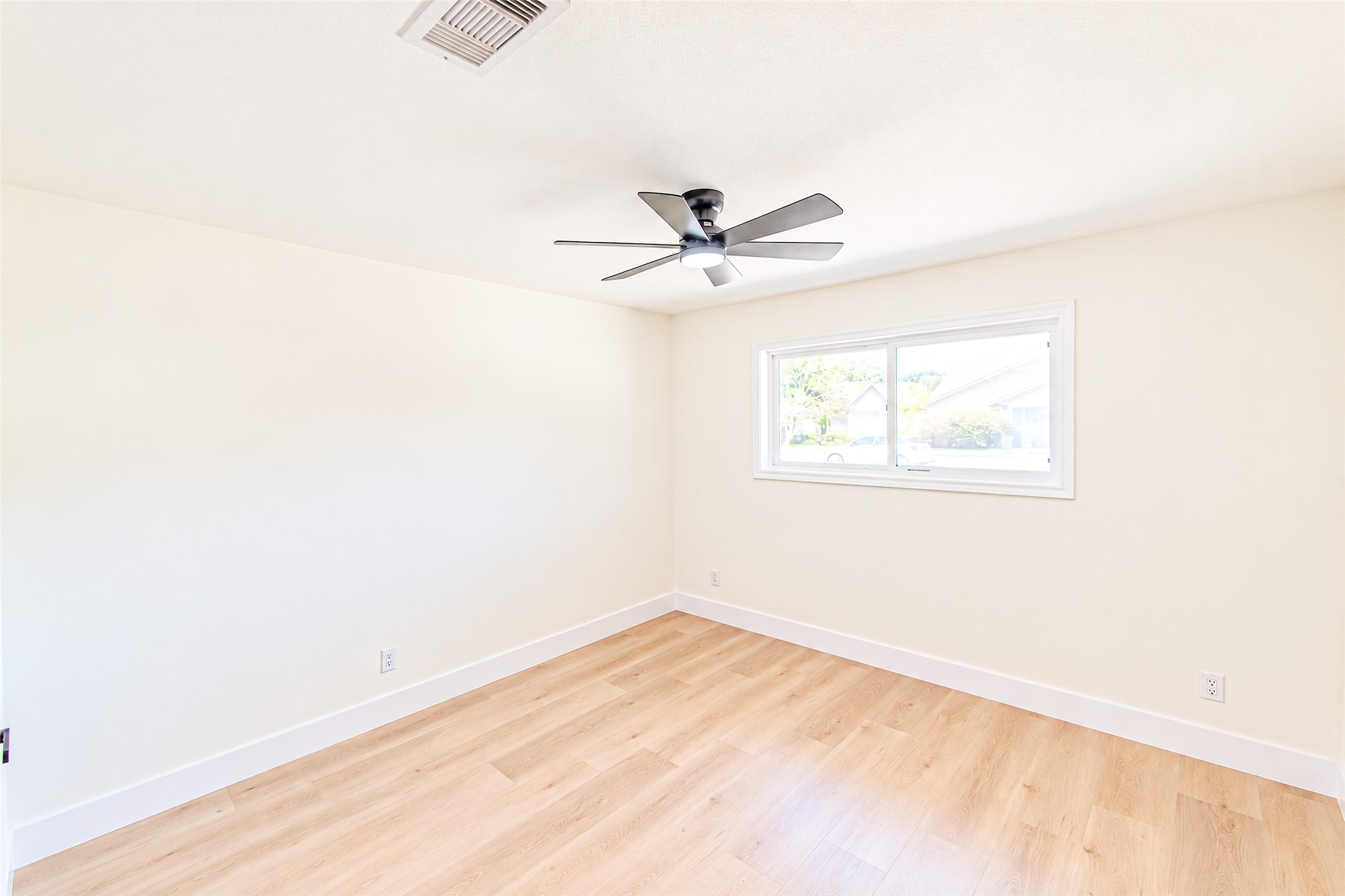 Experience tranquility in bedroom 2, featuring sleek hardwood floors, a modern ceiling fan, and abundant natural light through a large window.