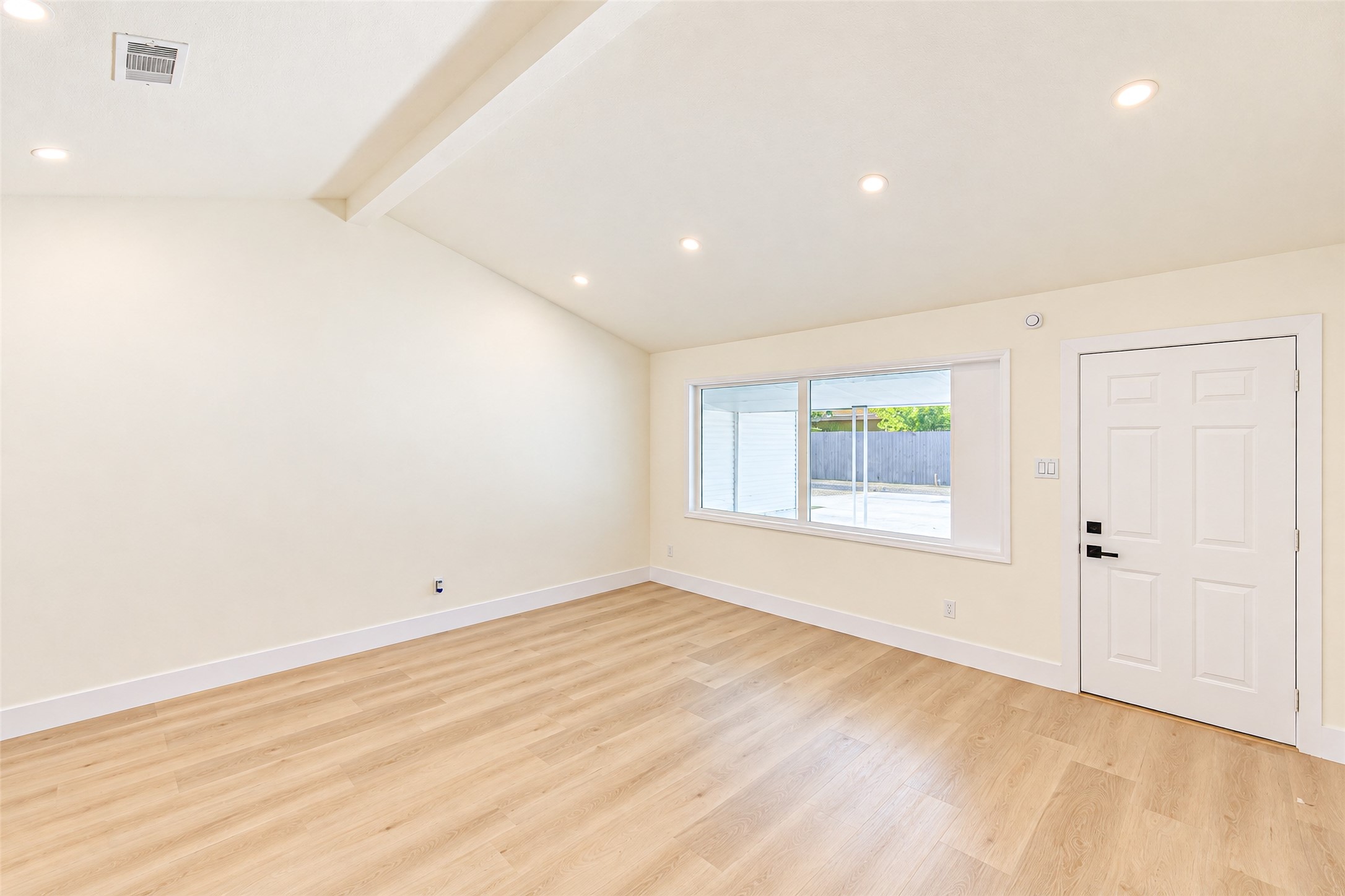 Experience the perfect blend of elegance and comfort in this bright, airy living space featuring vaulted ceilings, recessed lighting, large windows, and sleek hardwood flooring.