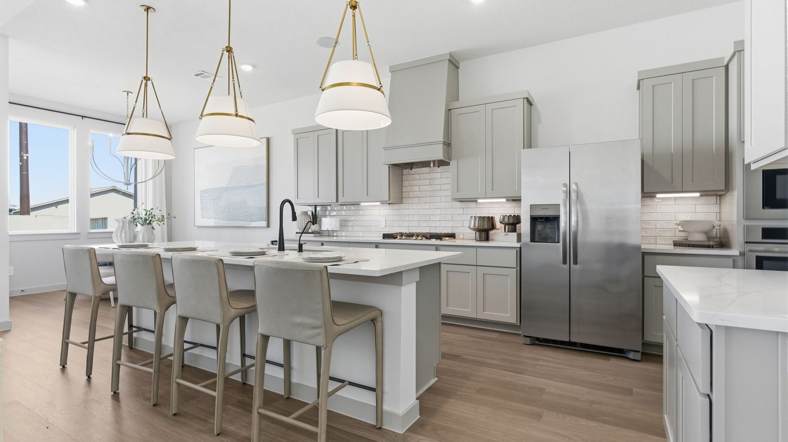 Luxurious and spacious kitchen with quartz countertops, stainless steel appliances, painted cabinets, expansive storage and an island with bar seating.