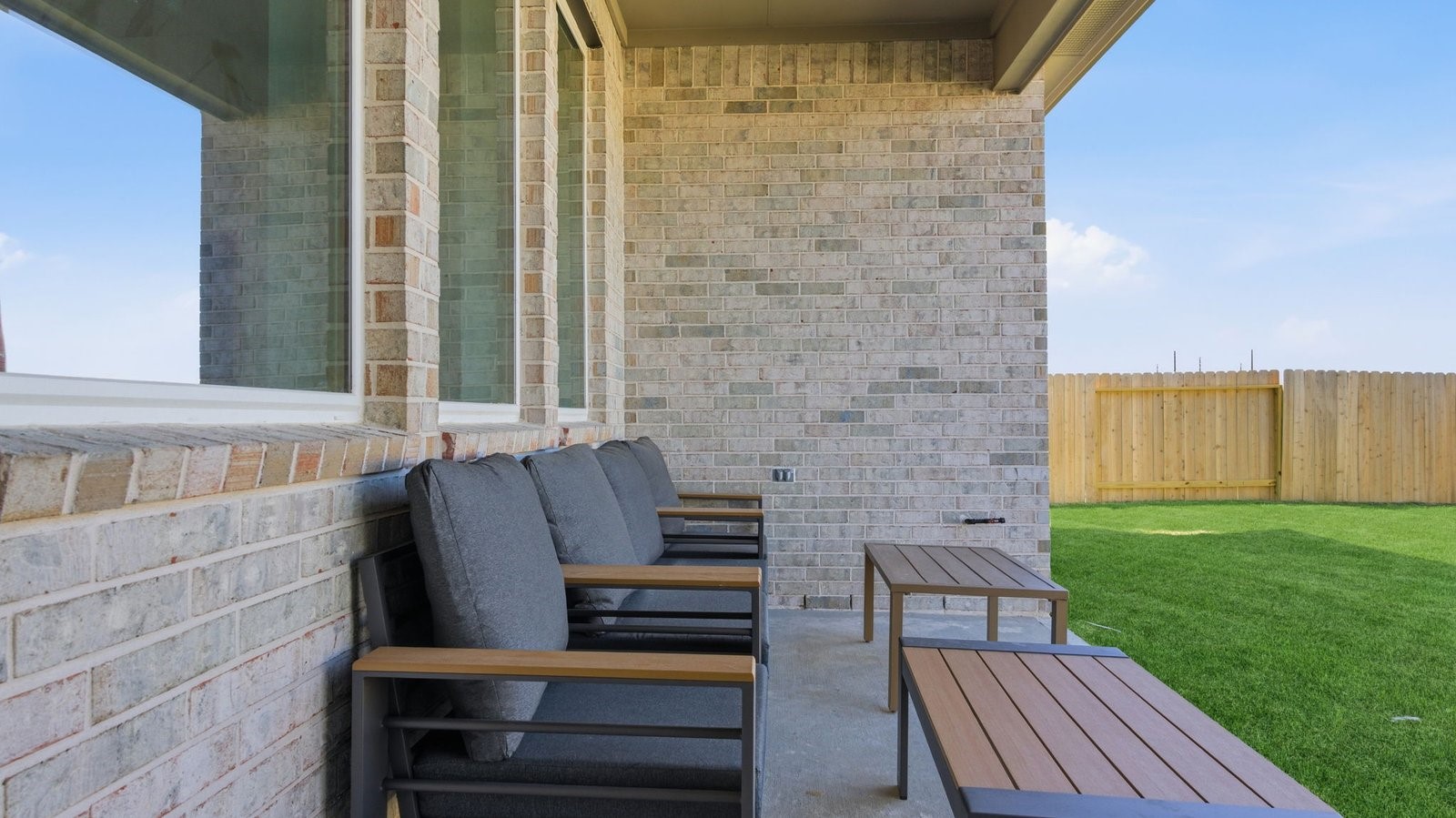 Outdoor covered patio with seating area overlooking a well-maintained lawn, perfect for relaxation.