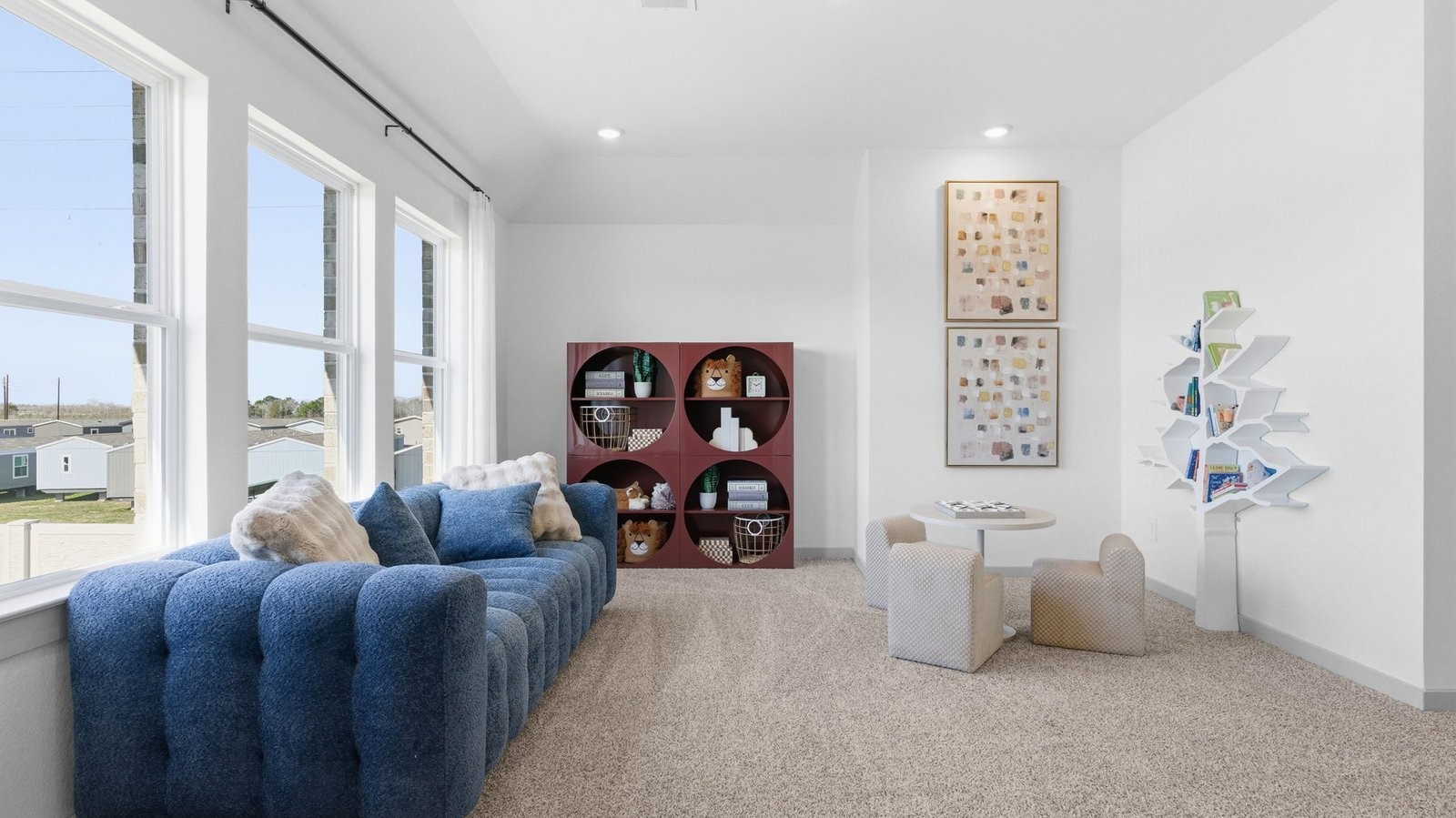 A spacious upstairs living area with plenty of natural light from windows overlooking side of the home