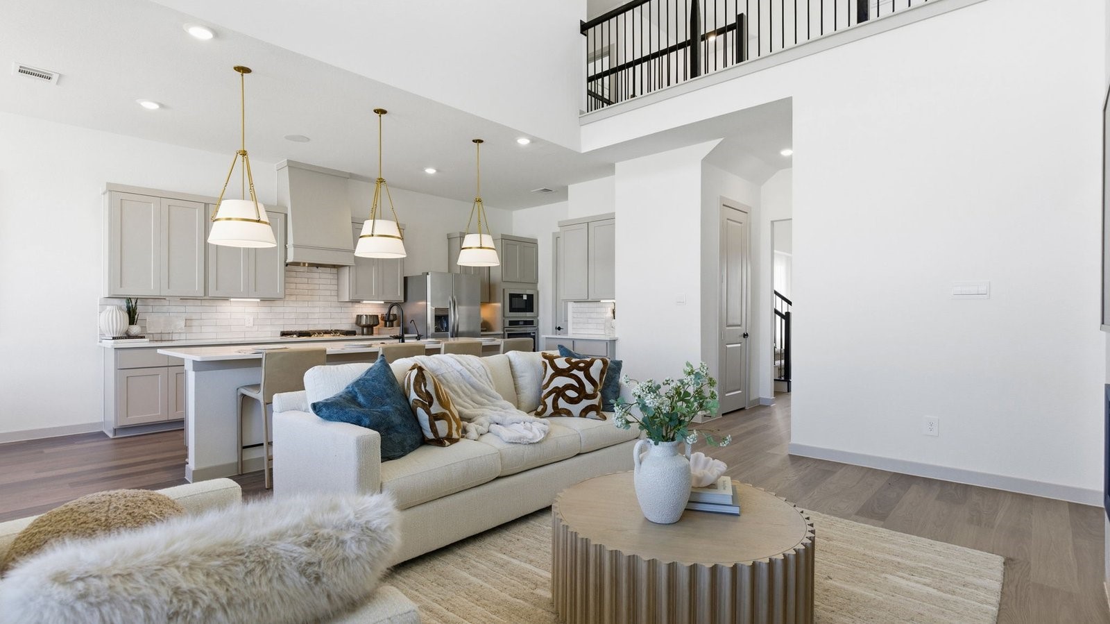 A luxurious living room featuring tall ceilings, large windows for natural lighting wood flooring and a view to the backyard.