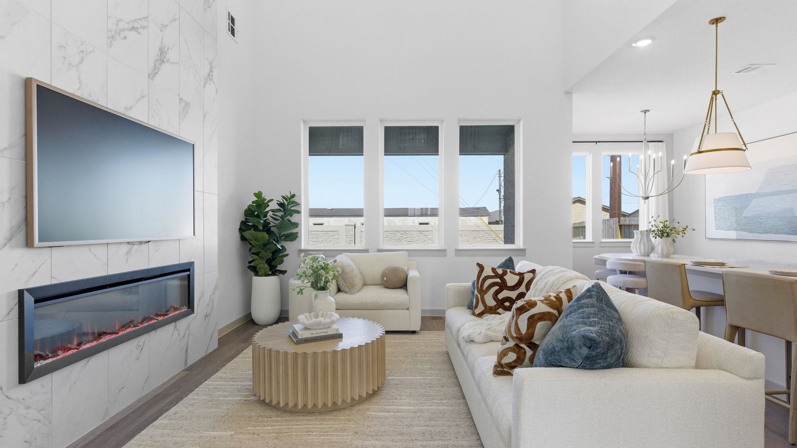 Elegant living room with soaring ceilings, a cozy electric fireplace, open-concept design, and seamless flow into a chef-inspired kitchen.