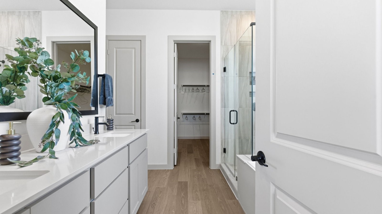 Luxurious primary bathroom with dual vanities, a soaking tub, and separate glass-enclosed walk in shower