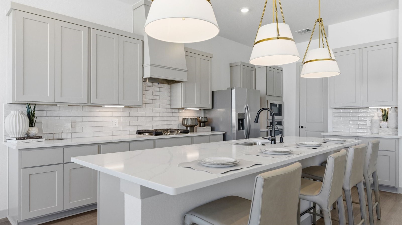 Luxurious and spacious kitchen with quartz countertops, stainless steel appliances, painted cabinets, expansive storage and an island with bar seating.