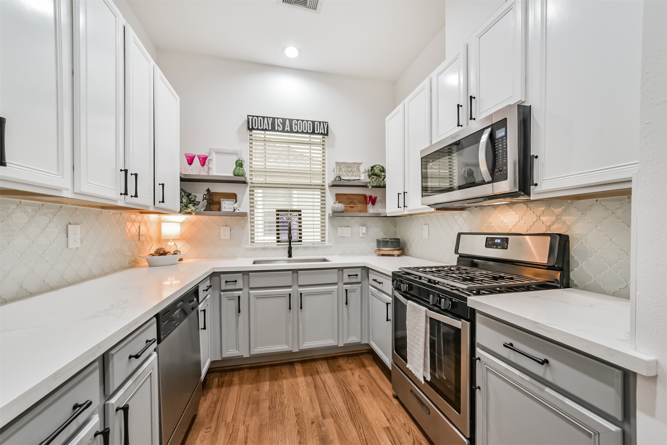 Bright, beautifully remodeled kitchen boasting quartzite counters, designer tile backsplash, stainless appliances, and charming open shelving