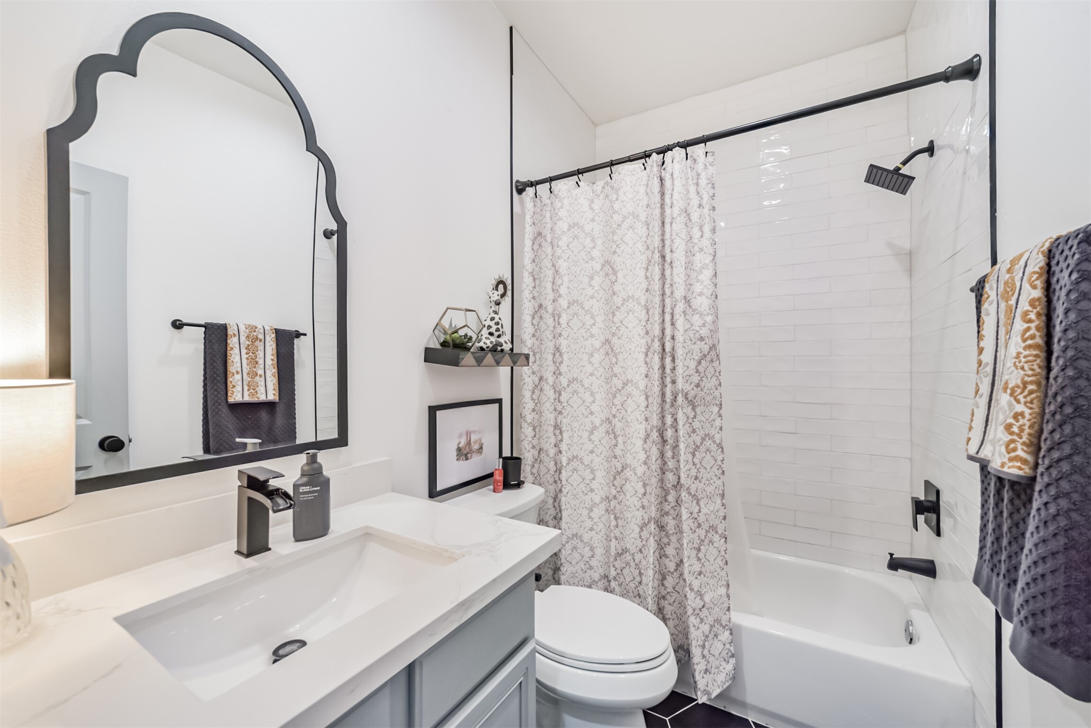 Secondary bathroom features lovely mirror, artisan-tile surround and hexagonal tile floors.