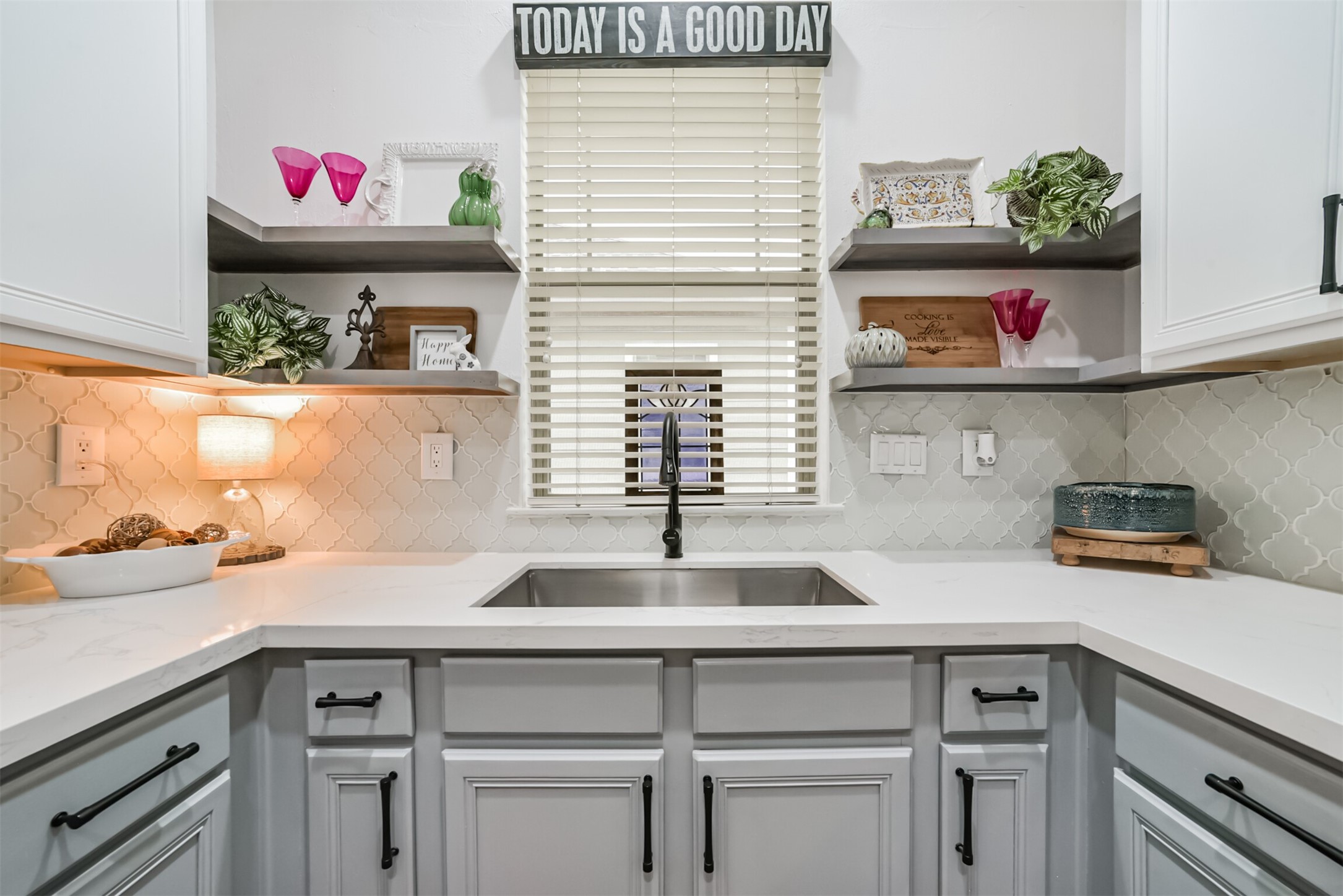 Charming window over the stainless sink, with open shelving and designer tile for effortless style