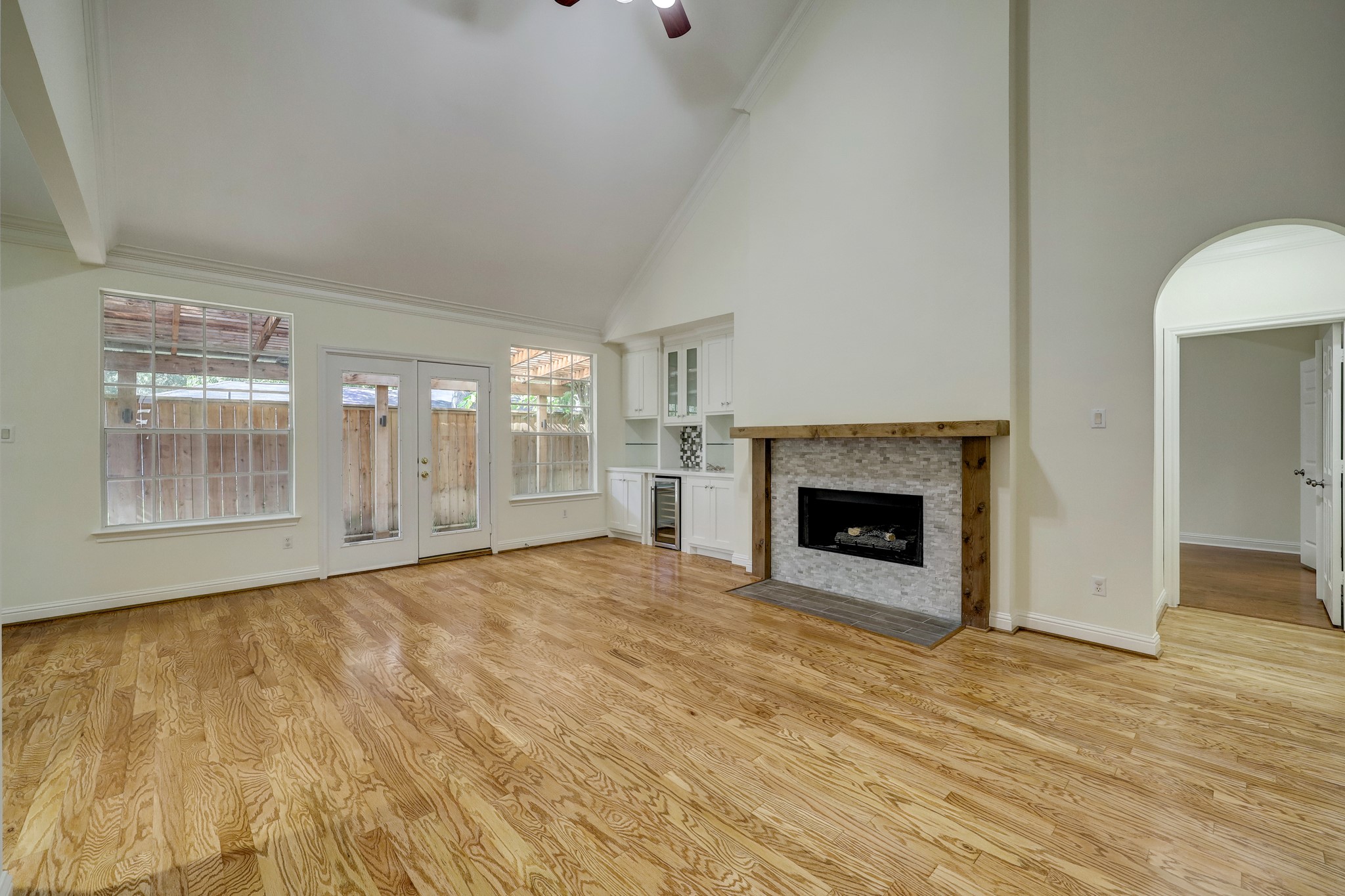 FAMILY ROOM (Unstaged): Bright and spacious with vaulted ceilings, hardwood floors, and a cozy fireplace with built-in cabinetry. Large windows and French doors bring in natural light and offer access to the backyard.