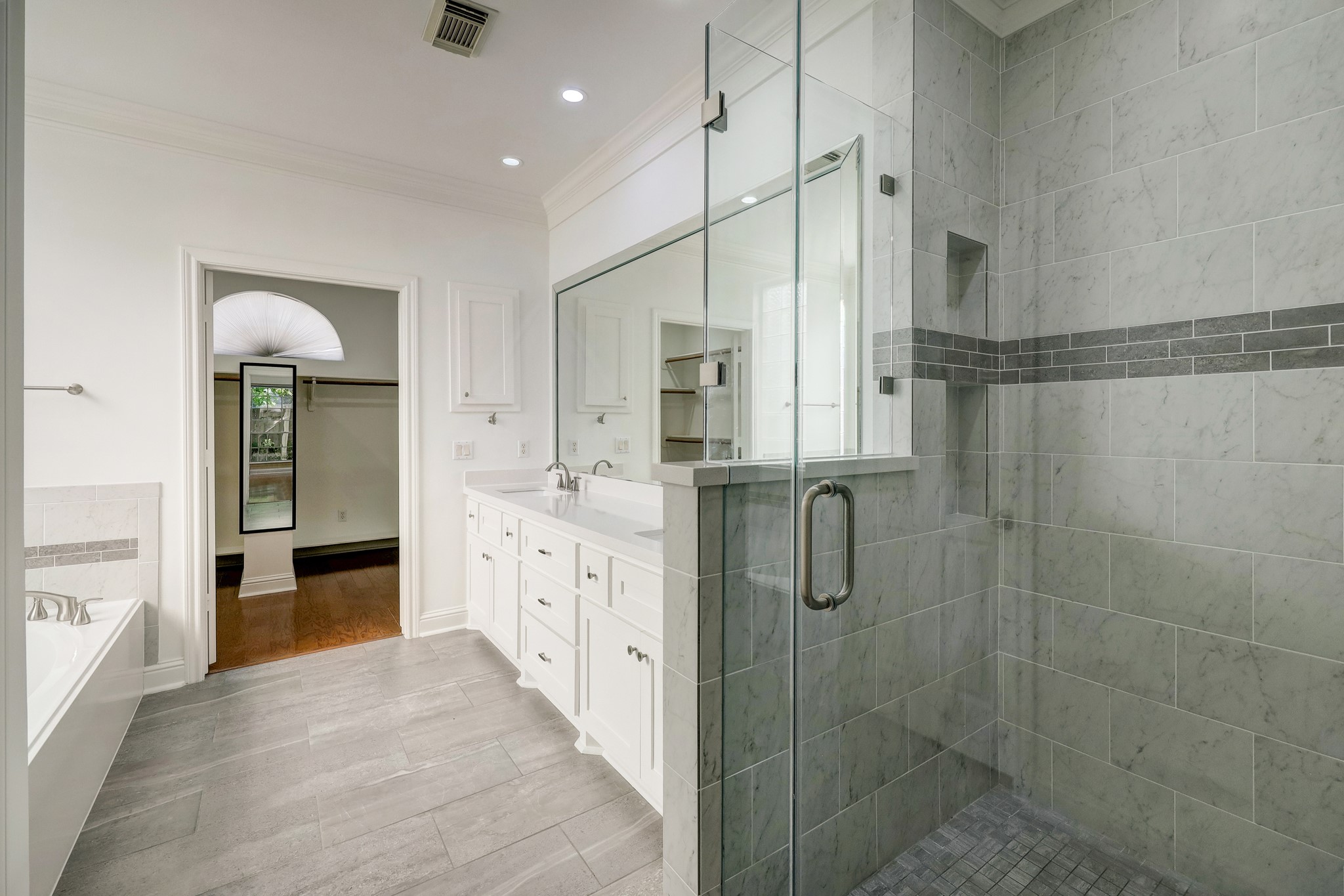 PRIMARY BATHROOM: Stylish and functional with a spacious walk-in shower, double vanity, and a generously sized walk-in closet tucked conveniently at the backperfect for organized living.