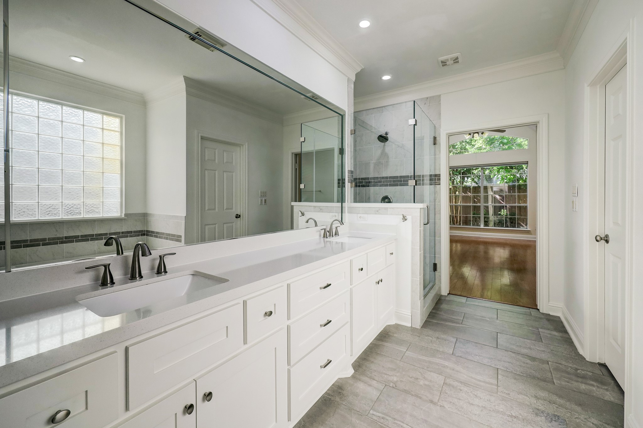 PRIMARY BATHROOM: Elegant and spacious with a double vanity, modern fixtures, and a glass-enclosed shower. Natural light enhances the neutral tones, creating a serene and functional retreat.