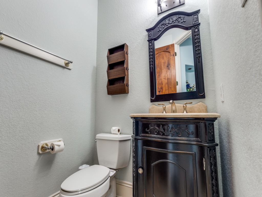 This is a 1/2 bathroom featuring a decorative vanity with a dark wood finish and intricate detailing. The light gray walls create a clean, fresh look.