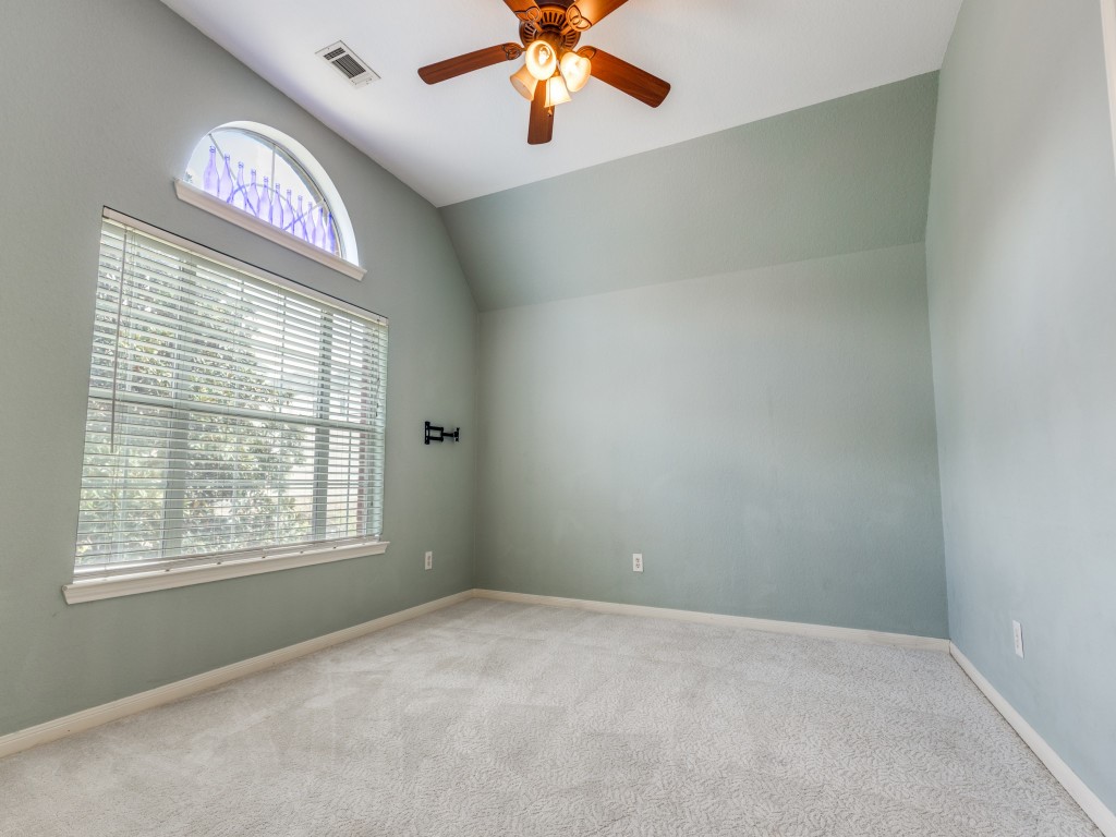Upstairs just off the landing is a spacious room with a large arched window and blinds, neutral carpeting, offering a cozy and versatile space which can be utilized as a game room or office area.