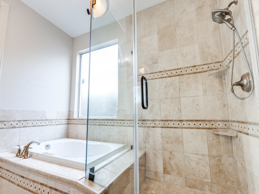 This bathroom features a luxurious glass-enclosed shower with elegant tile work and a nearby soaking tub, providing a spa-like atmosphere.
