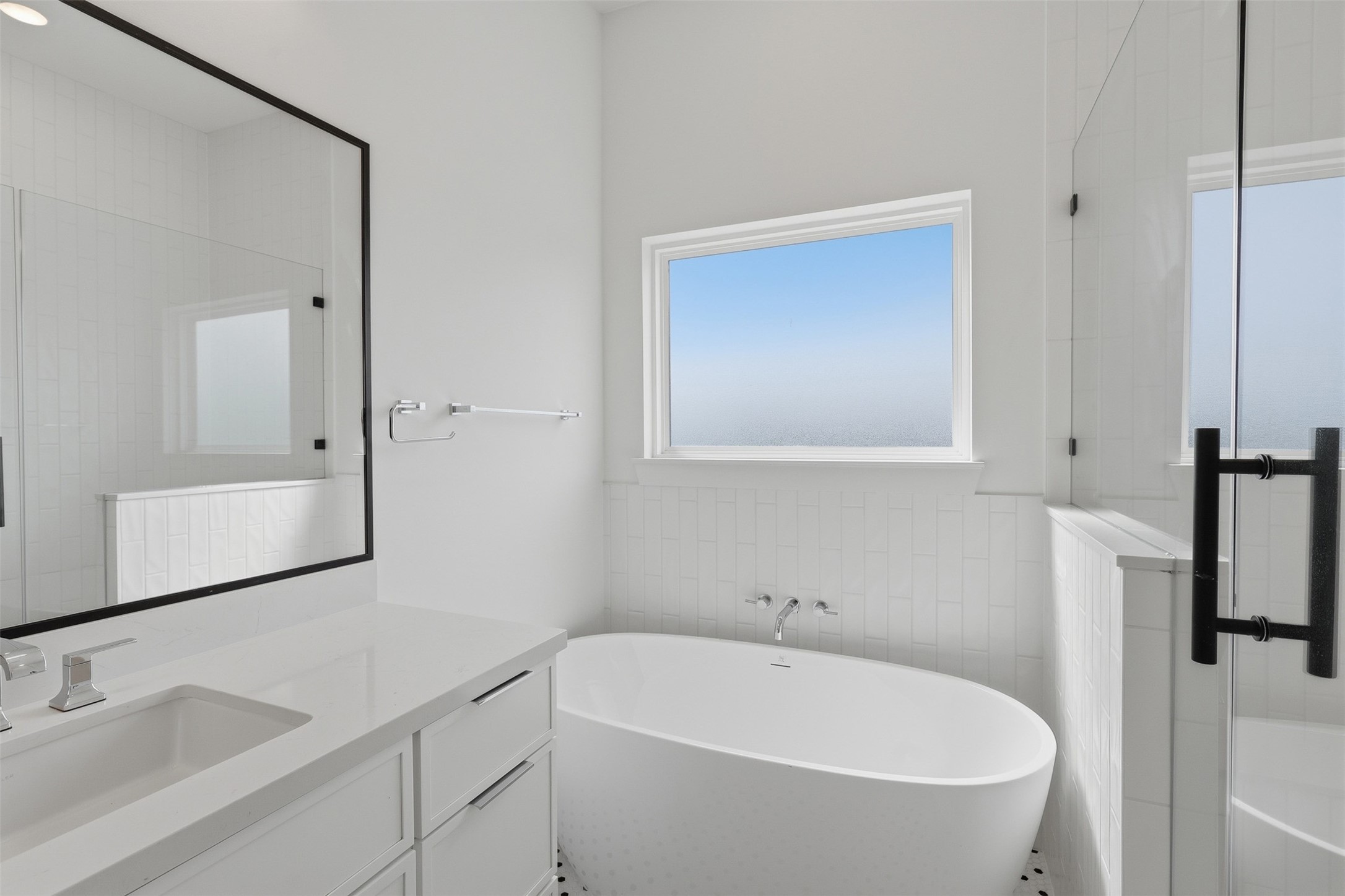 A freestanding tub sits beside the window, with a separate shower alongside it.