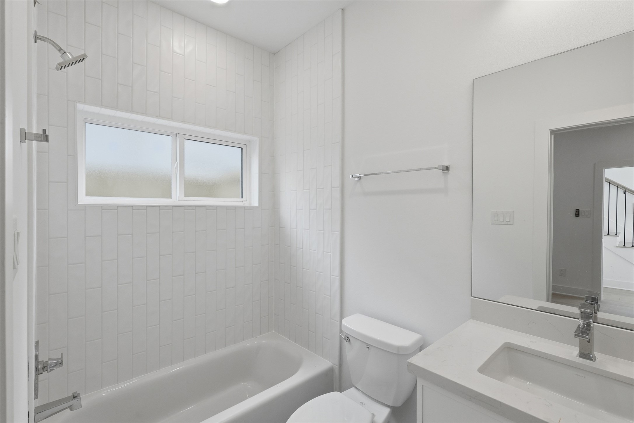 This bathroom also includes a tub and shower combination, with a window above.