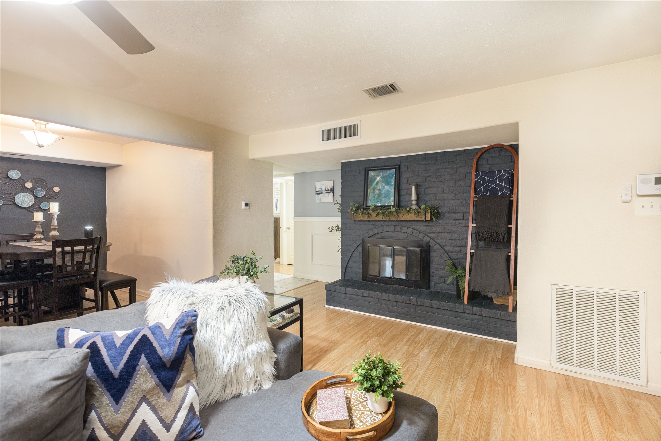 Cozy living area featuring a stylish black brick fireplace, warm wood flooring, and an open flow into the dining space, perfect for entertaining.