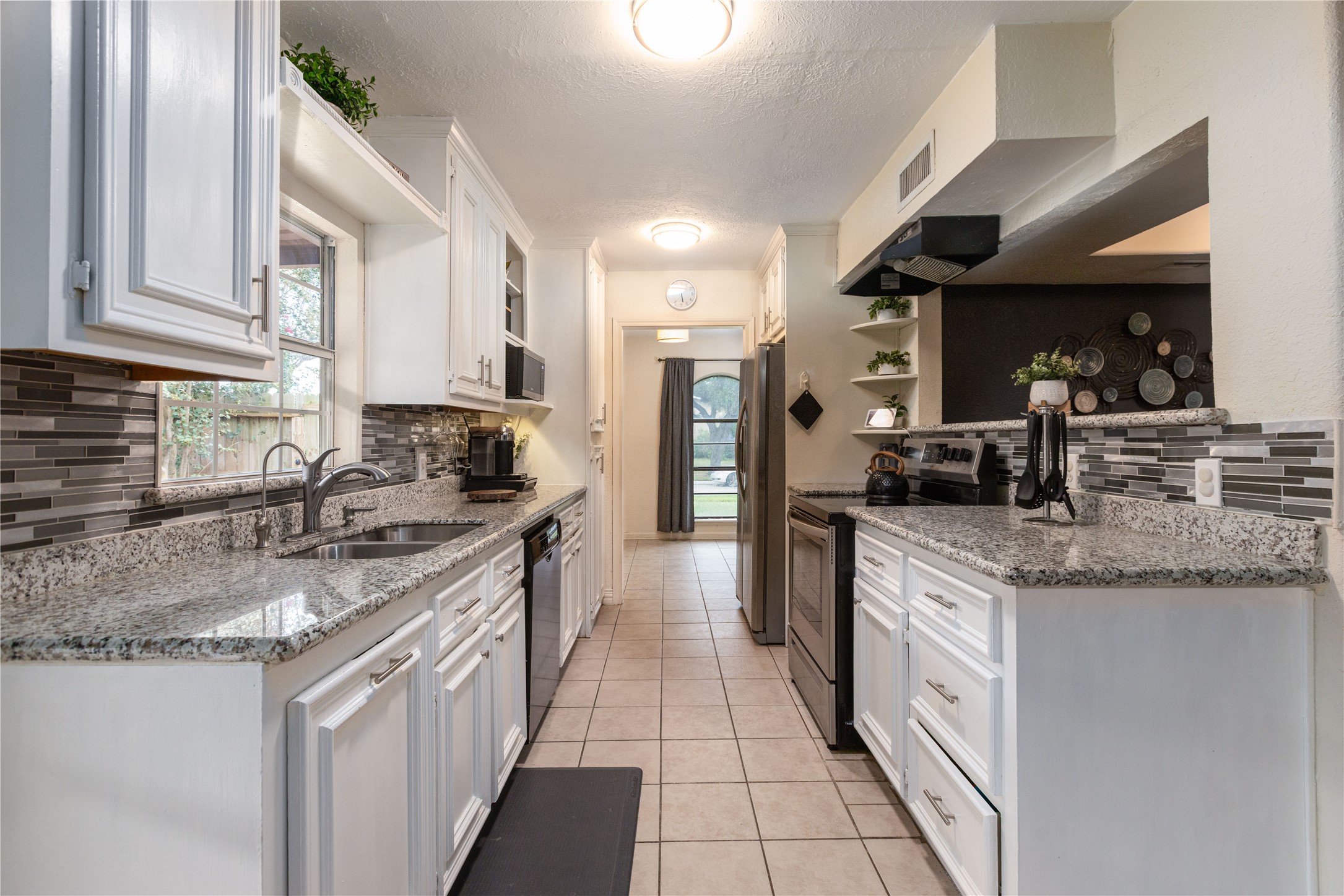 Charming galley kitchen with sleek granite countertops, modern tile backsplash, and ample cabinetry, offering a bright and functional space for cooking and entertaining.