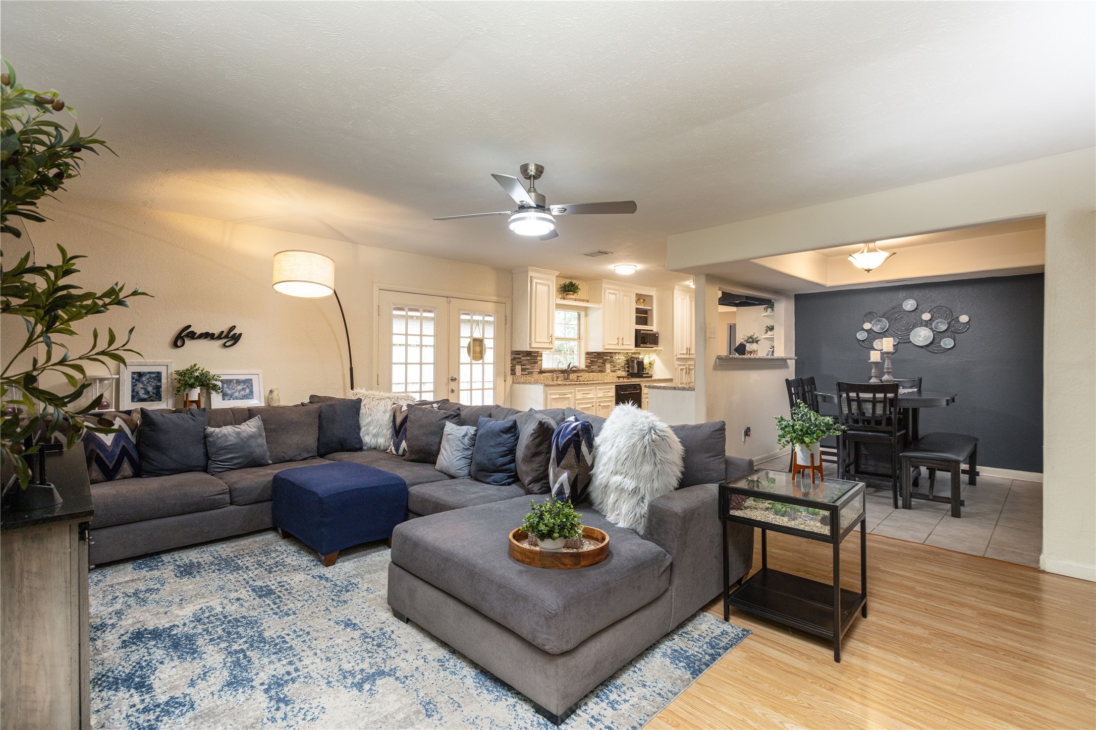Spacious open-concept living area featuring a cozy sectional sofa, stylish decor, and a seamless flow into the dining and kitchen spaces with modern finishes.