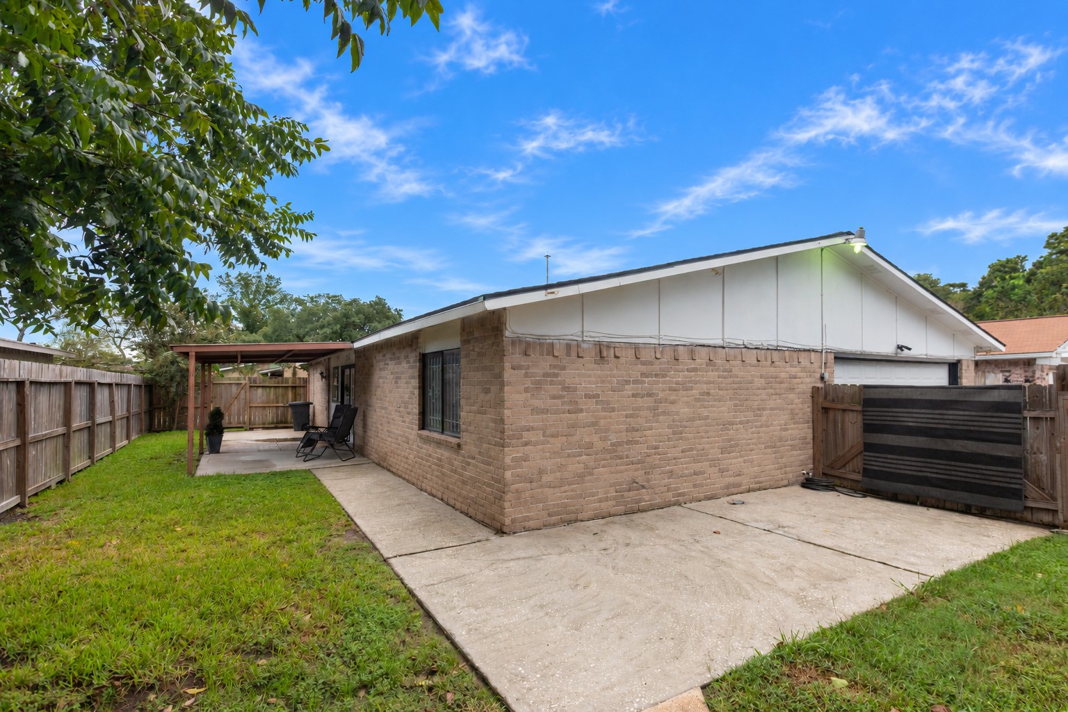 Charming backyard features a covered patio perfect for outdoor relaxation, surrounded by a privacy fence and lush greenery.