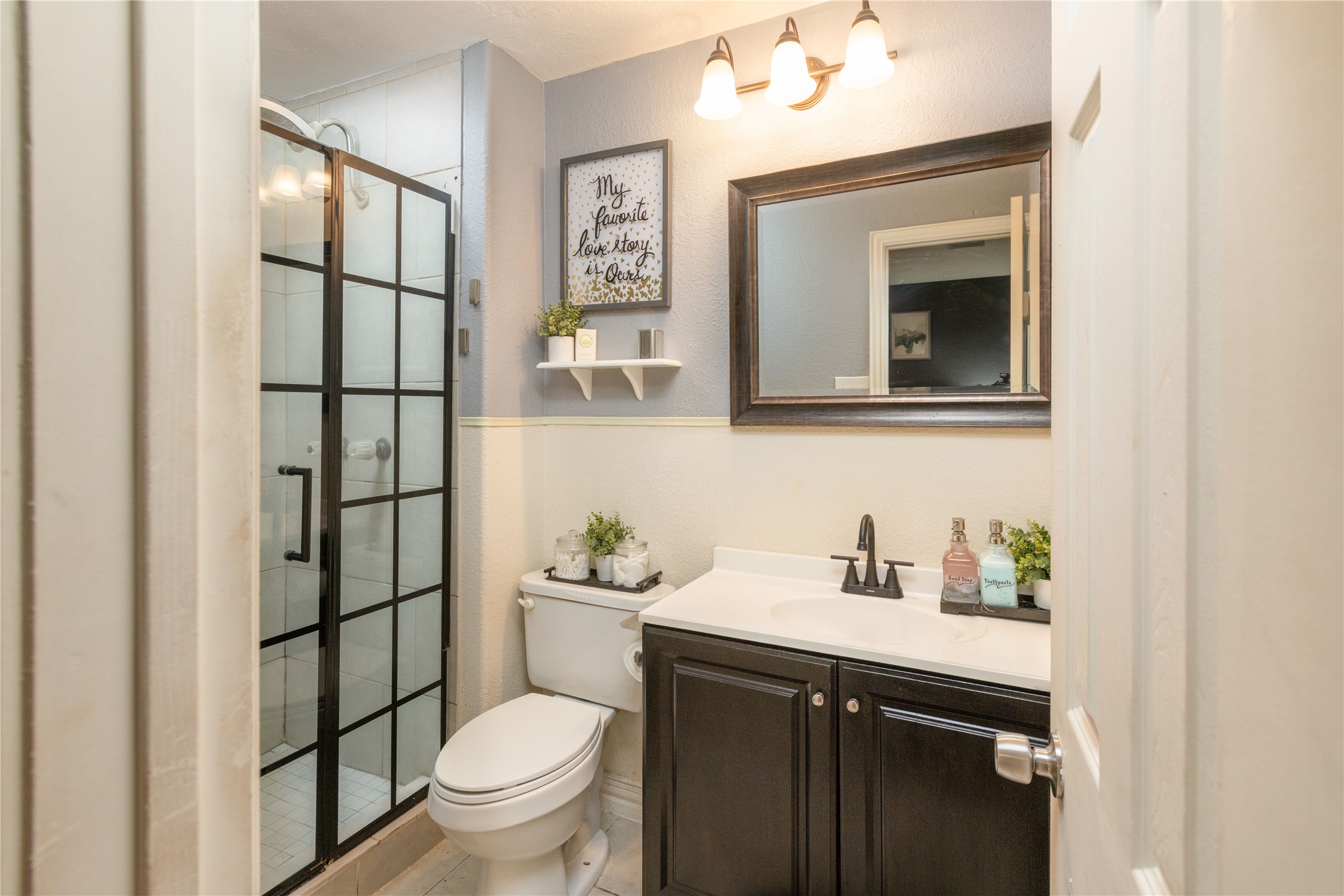 Chic bathroom with a modern glass-enclosed shower, elegant vanity, and stylish lighting, offering a fresh and inviting space.