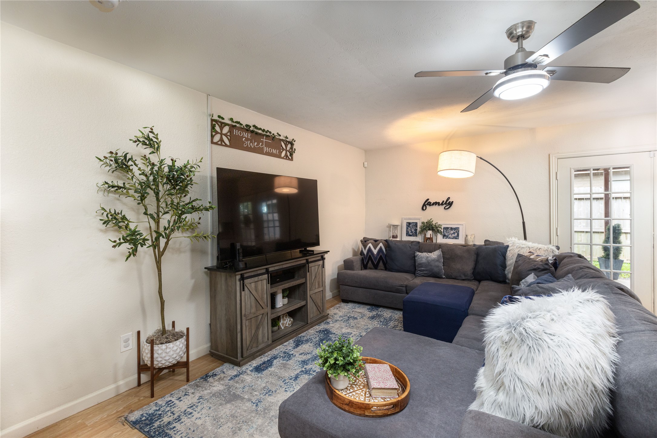 Cozy living room featuring a large sectional sofa, modern ceiling fan, and stylish decor, perfect for family gatherings.
