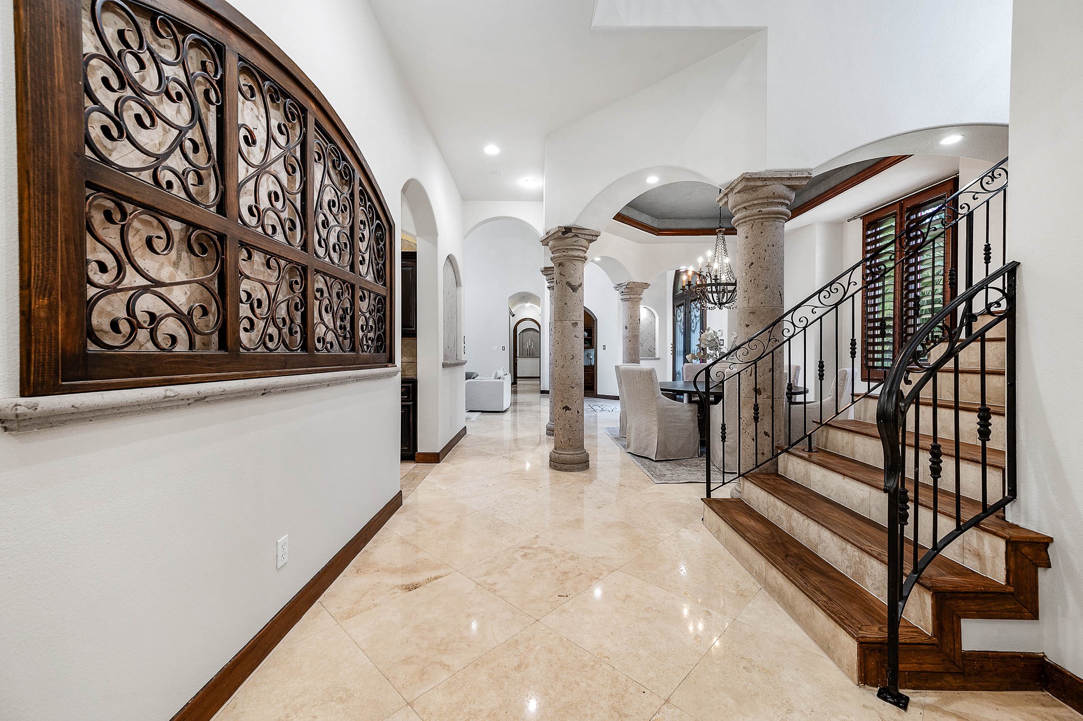 The staircase features wood treads and an elegant wrought iron balustrade leading to the second floor.